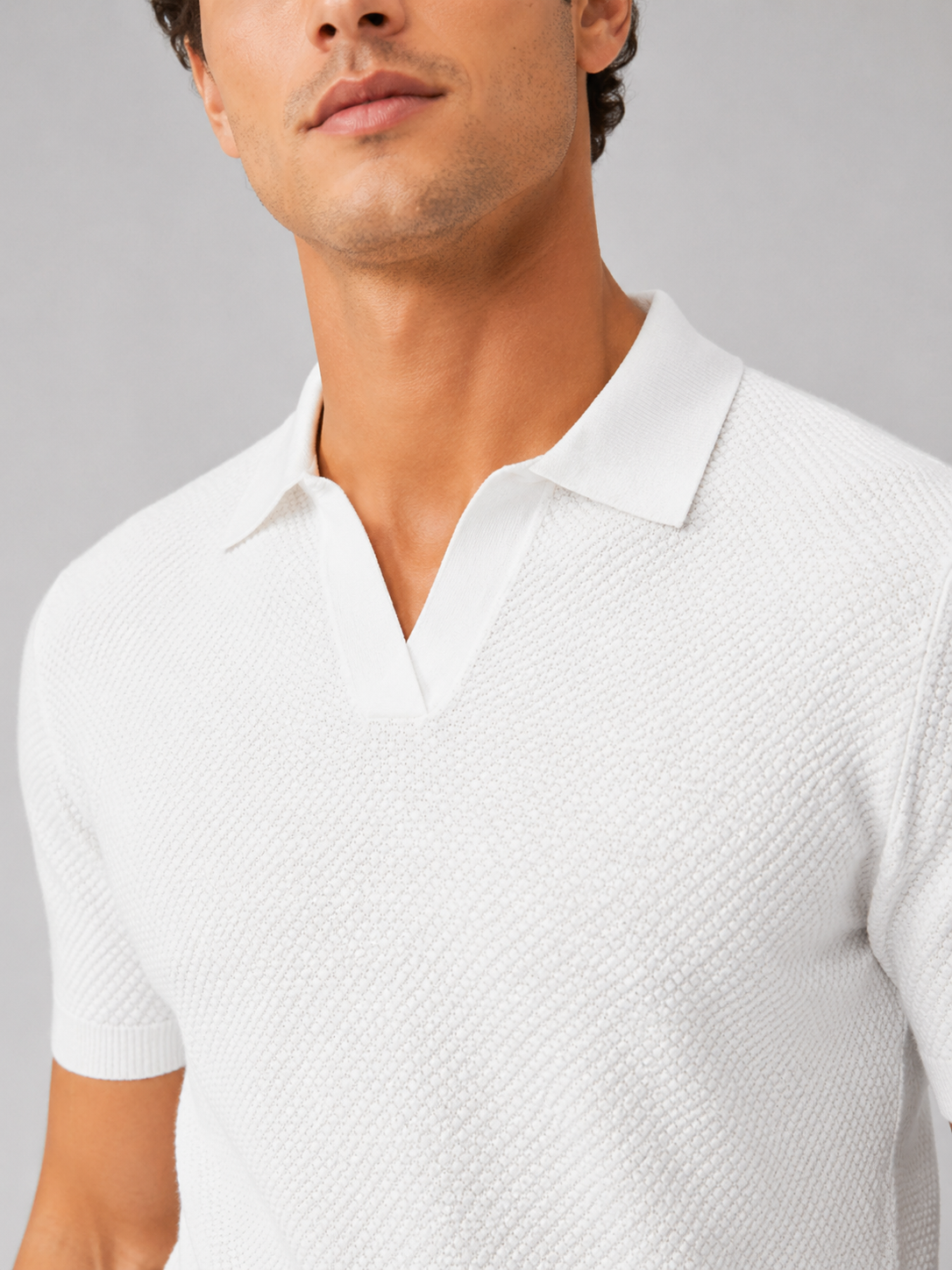 Close up of white knit polo showing soft breathable stretch fabric and refined collar detail