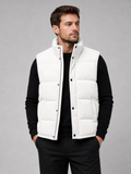Front view of a man wearing a white corduroy puffer vest with a stand collar, padded construction, and full zip front