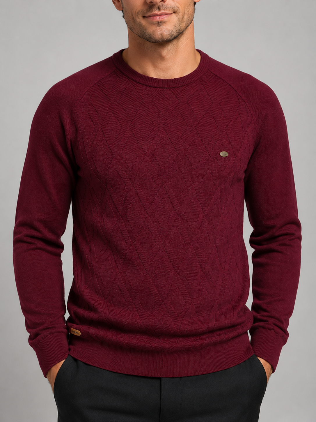 Close-up of a wine argyle sweater showing the diamond knit pattern, crew neckline, ribbed cuffs, hem, and warm texture