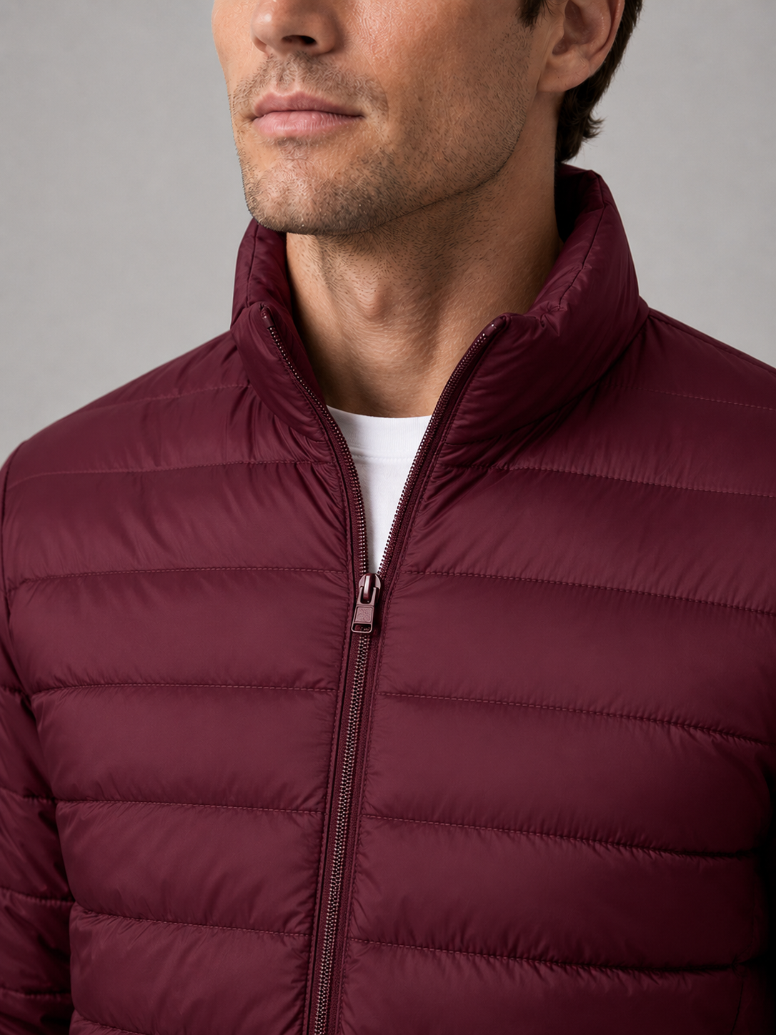 Close up of wine down puffer jacket showing insulated quilting, stand collar, and weather resistant fabric detail