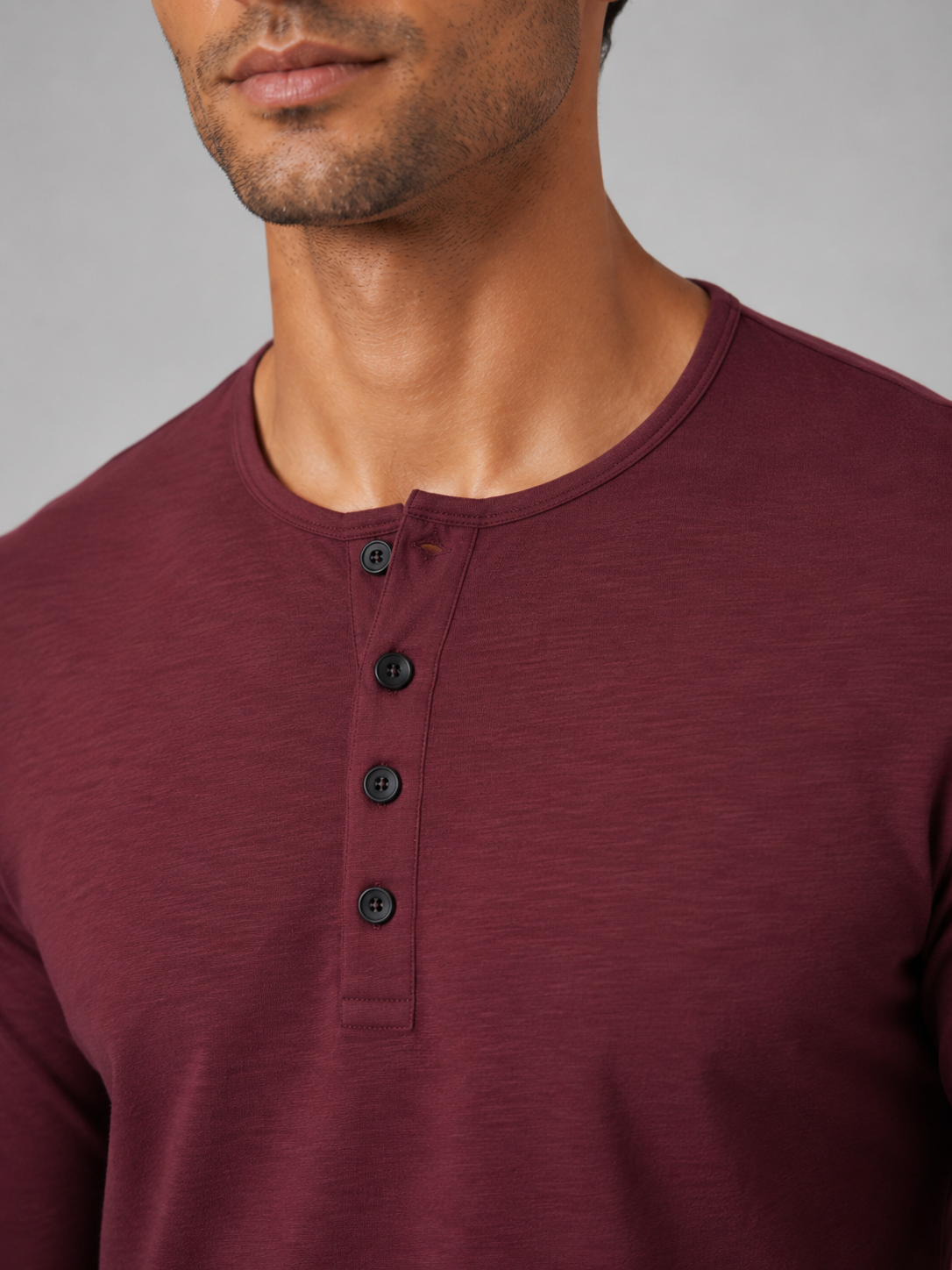 Close up of wine henley shirt fabric showing soft smooth breathable texture and button detail