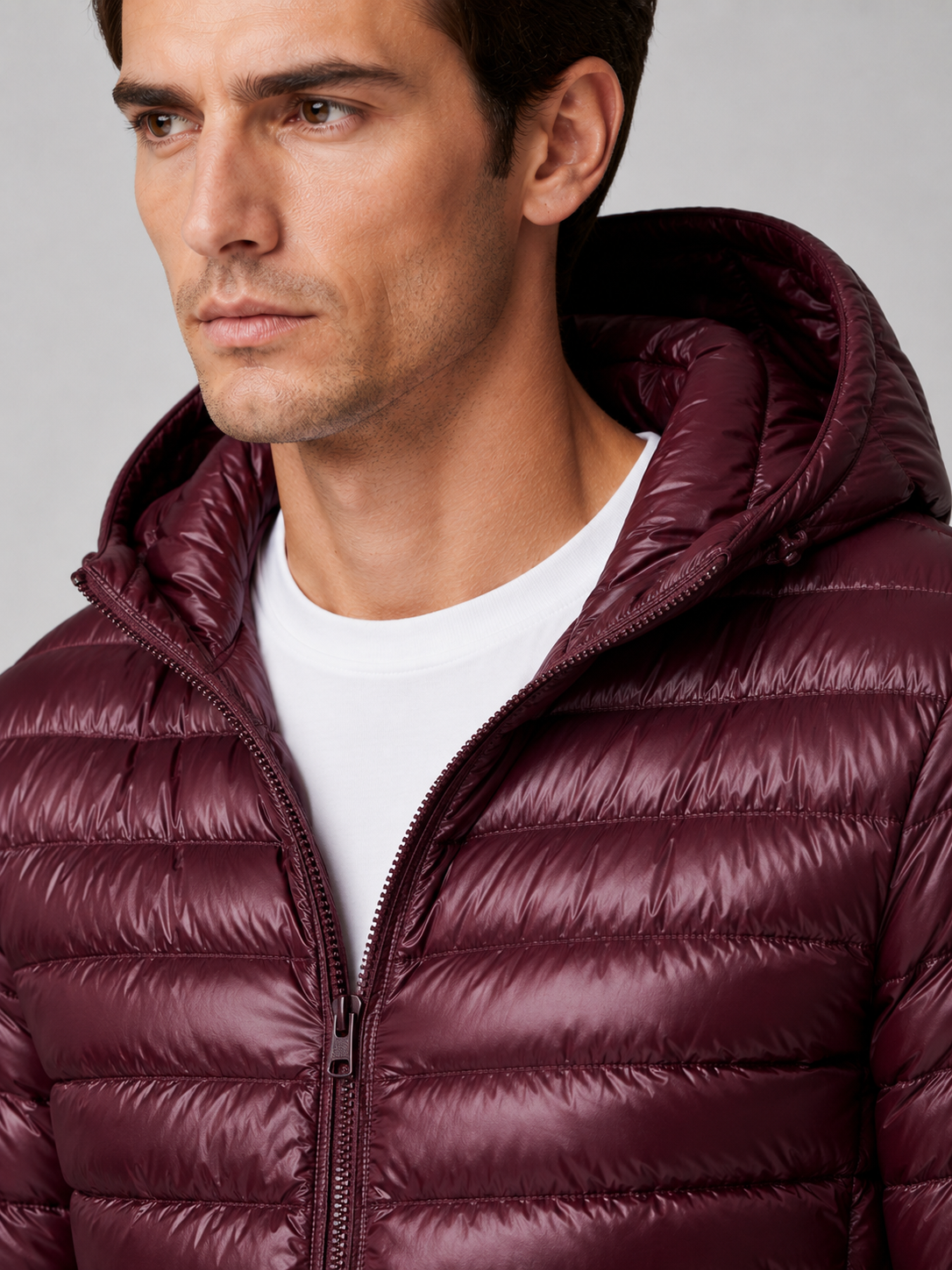 Close up of wine hooded down jacket showing lightweight quilted insulation, attached hood, and weather resistant fabric detail