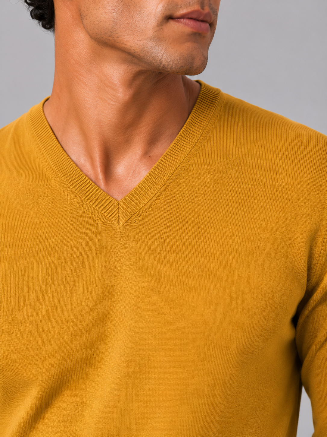 Close up of yellow knit sweater showing soft lightweight fabric and refined v neck detail