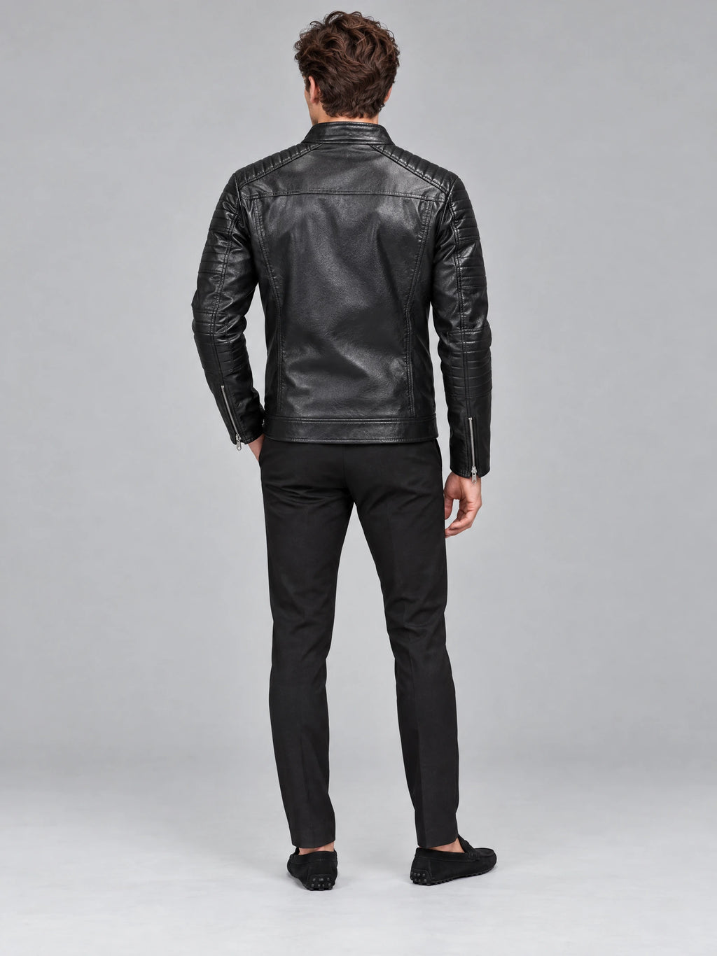 Rear studio view of a model wearing a Black Biker Leather Jacket with quilted shoulder and sleeve panels, plus zippered cuffs.
