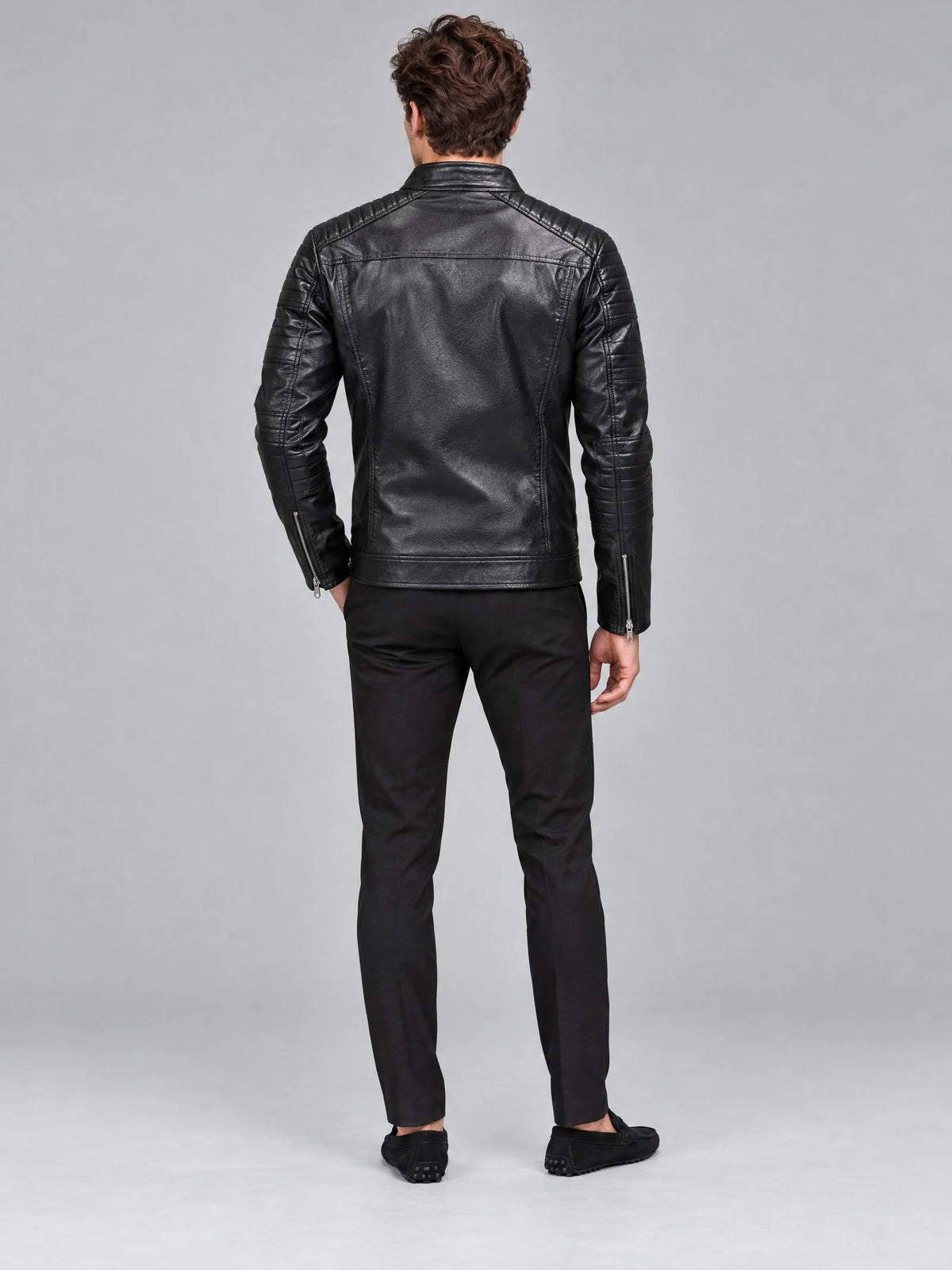 Rear studio view of a model wearing a Black Biker Leather Jacket with quilted shoulder and sleeve panels, plus zippered cuffs.