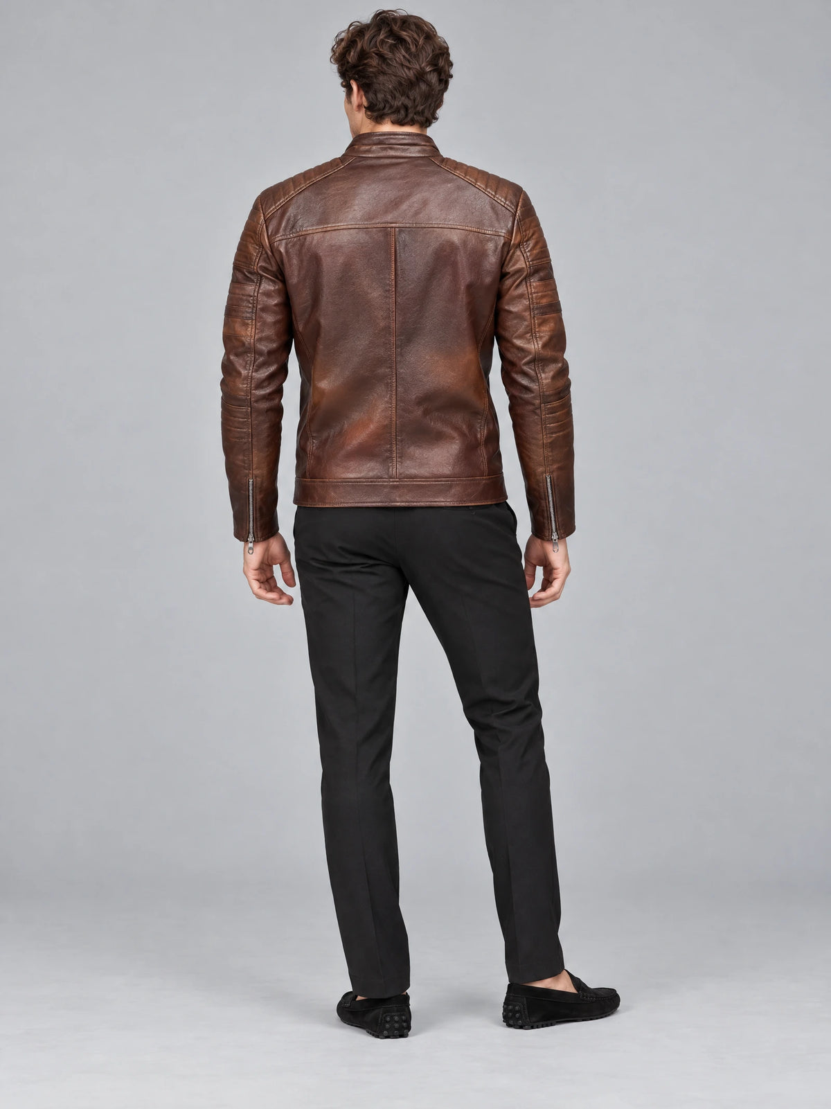 Rear view of a model wearing a Brown Biker Leather Jacket with quilted shoulder panels, back seams, and zippered cuffs.