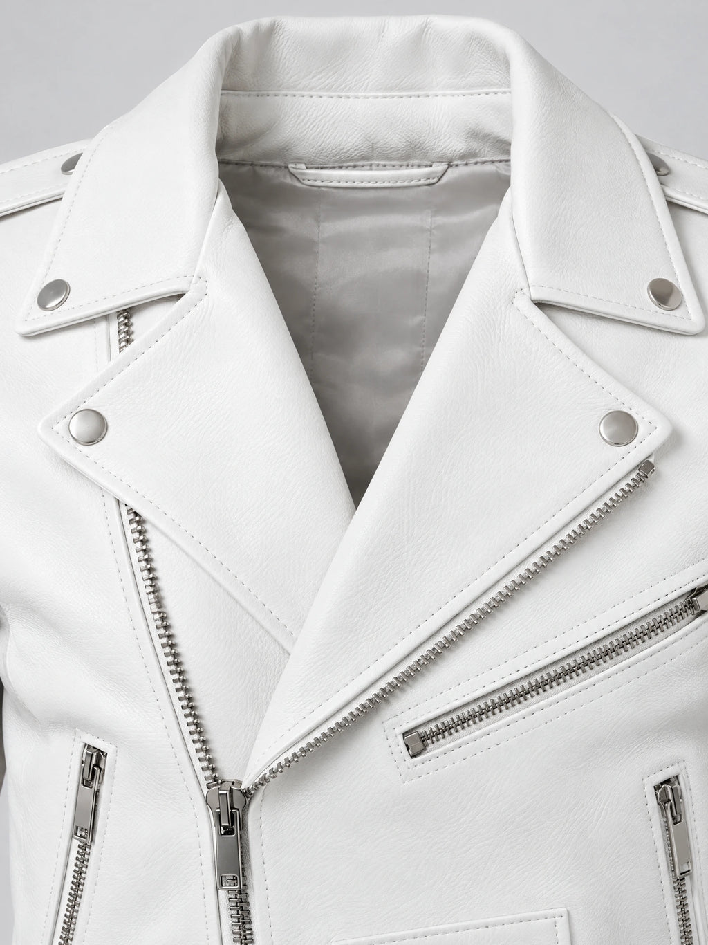 Close-up of a White Biker Leather Jacket showing the notched collar, snap tabs, textured PU leather, and silver diagonal zipper.