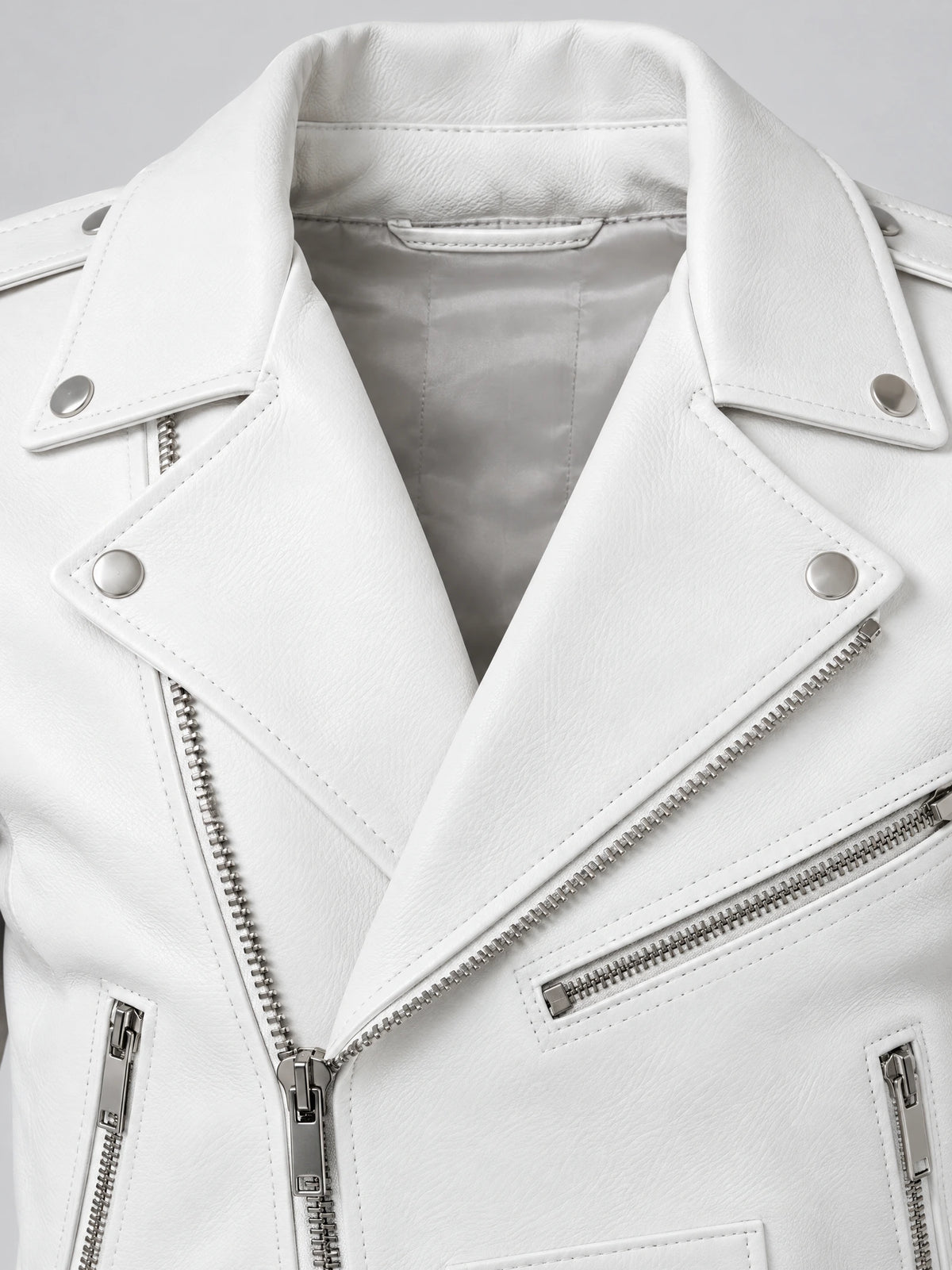 Close-up of a White Biker Leather Jacket showing the notched collar, snap tabs, textured PU leather, and silver diagonal zipper.