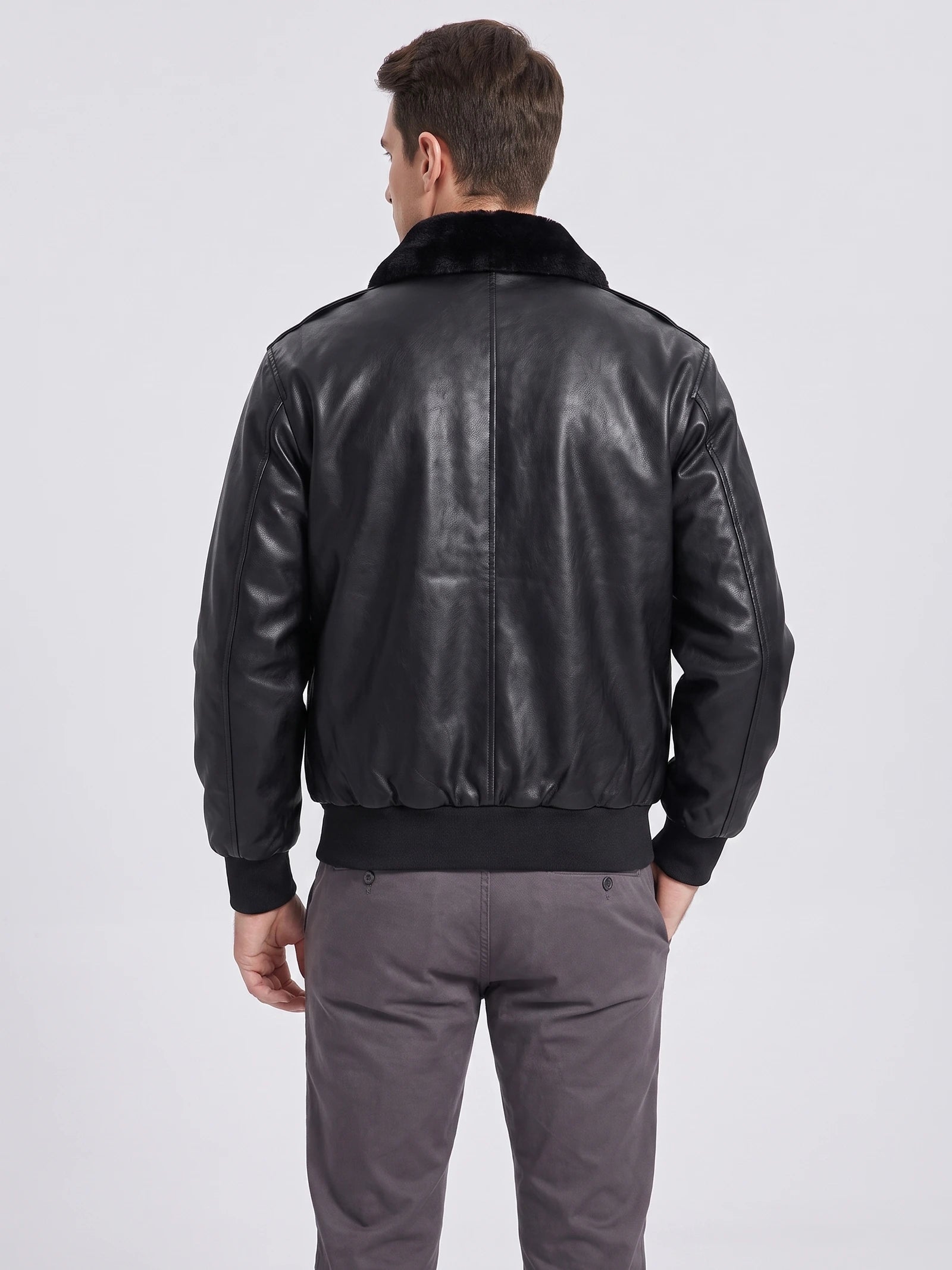 Rear view of a model wearing a Black leather jacket with a plush collar, center-back seam, and ribbed hem and cuffs.