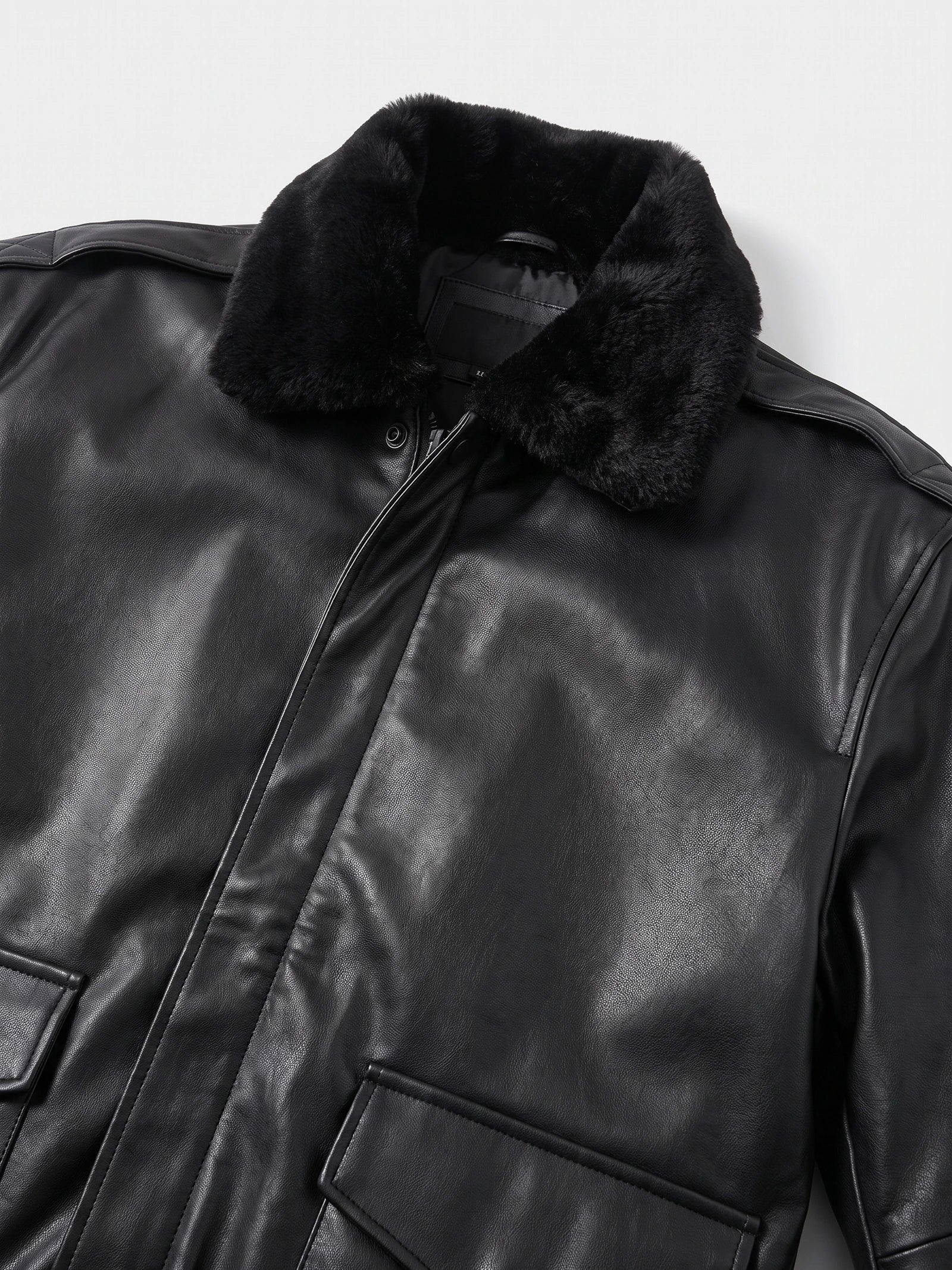 Close-up of the Black leather jacket showing its plush collar, front zipper, and flap pockets.