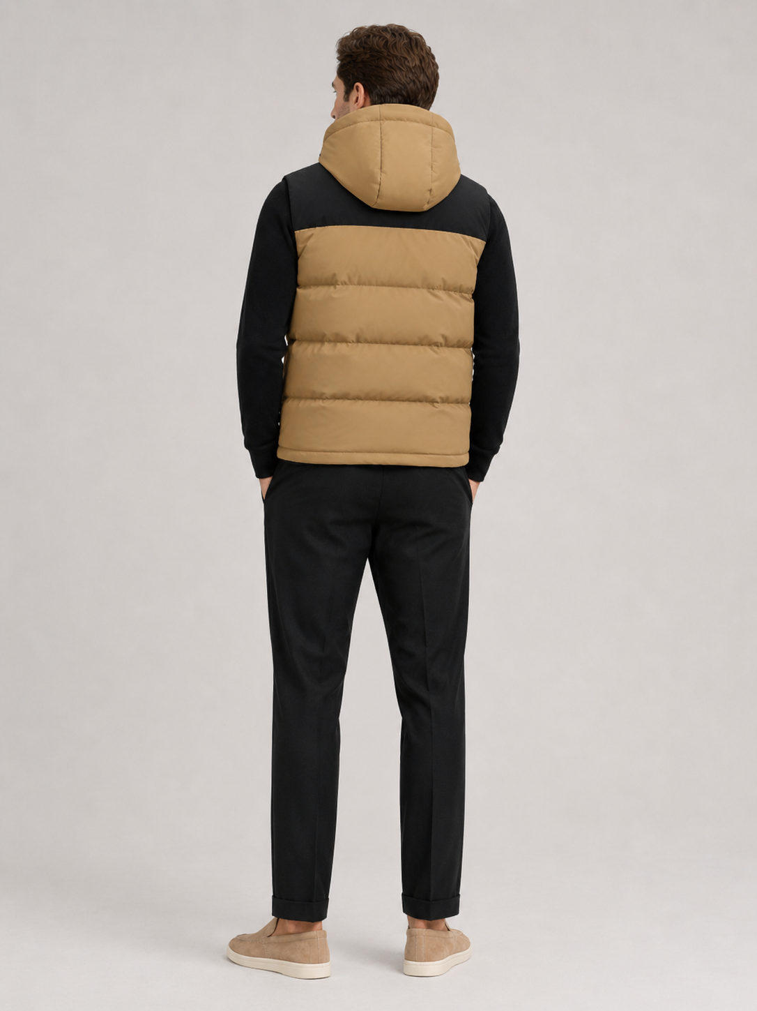 Back view of a man wearing a brown hooded puffer vest showing the attached hood, padded construction, sleeveless cut, and comfortable fit