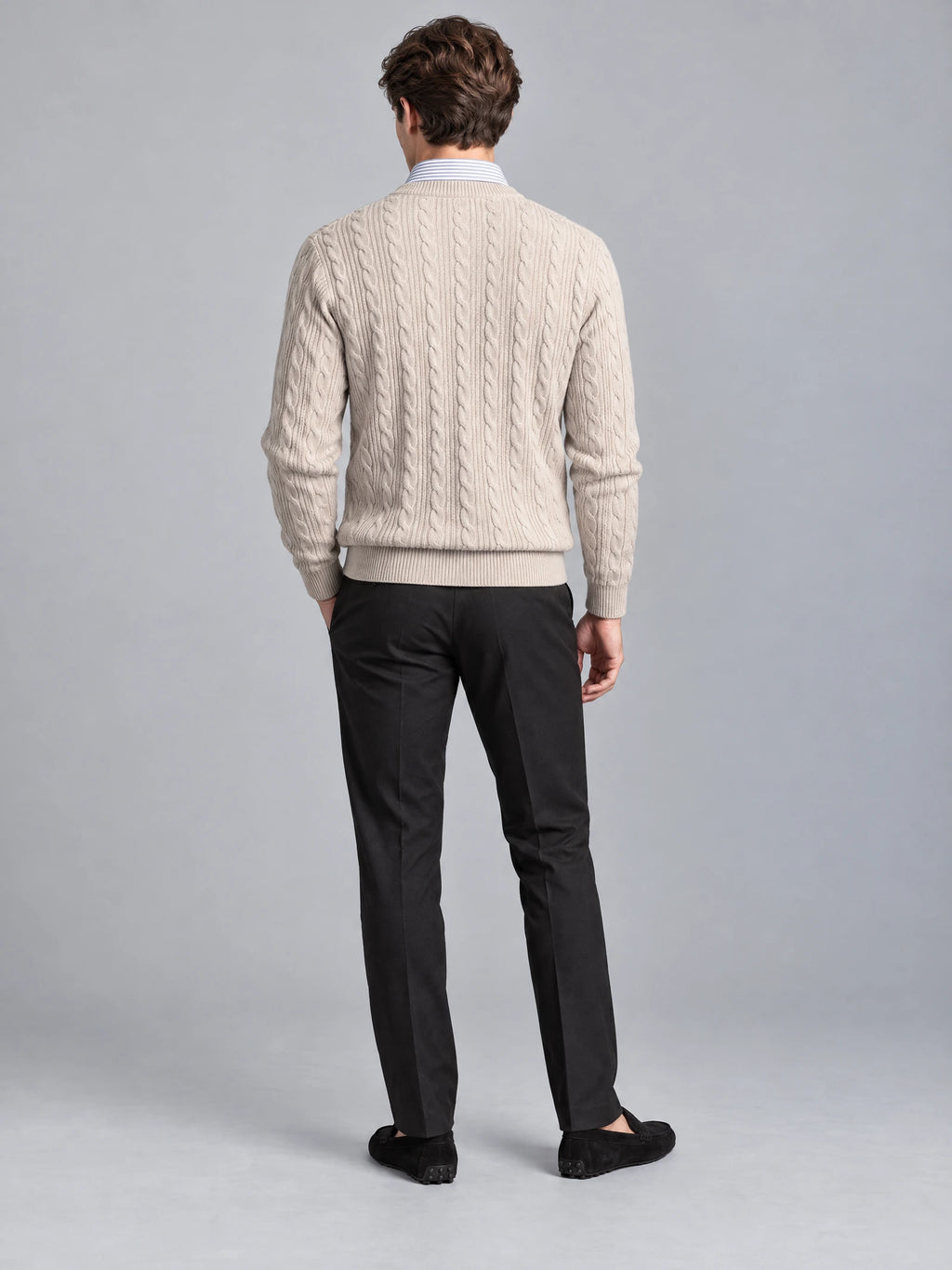 Rear studio view of a model wearing a Beige business casual knitted pullover sweater with vertical cable-knit texture and ribbed hem and cuffs.