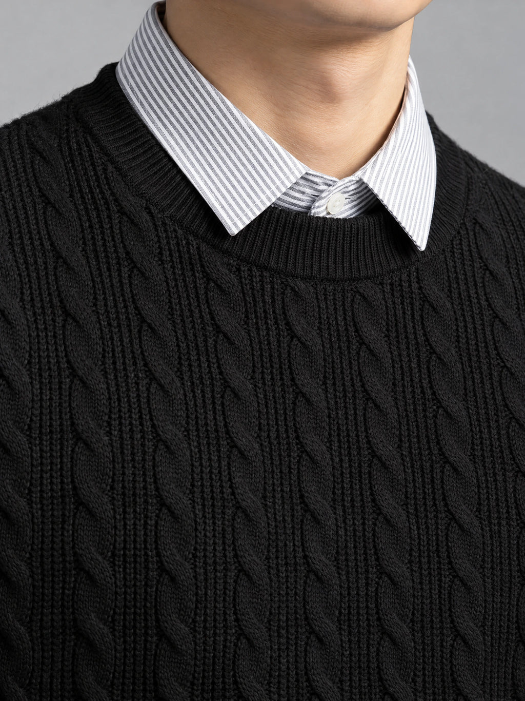 Close-up of a Black business casual knitted pullover sweater with cable-knit texture and a faux shirt collar.