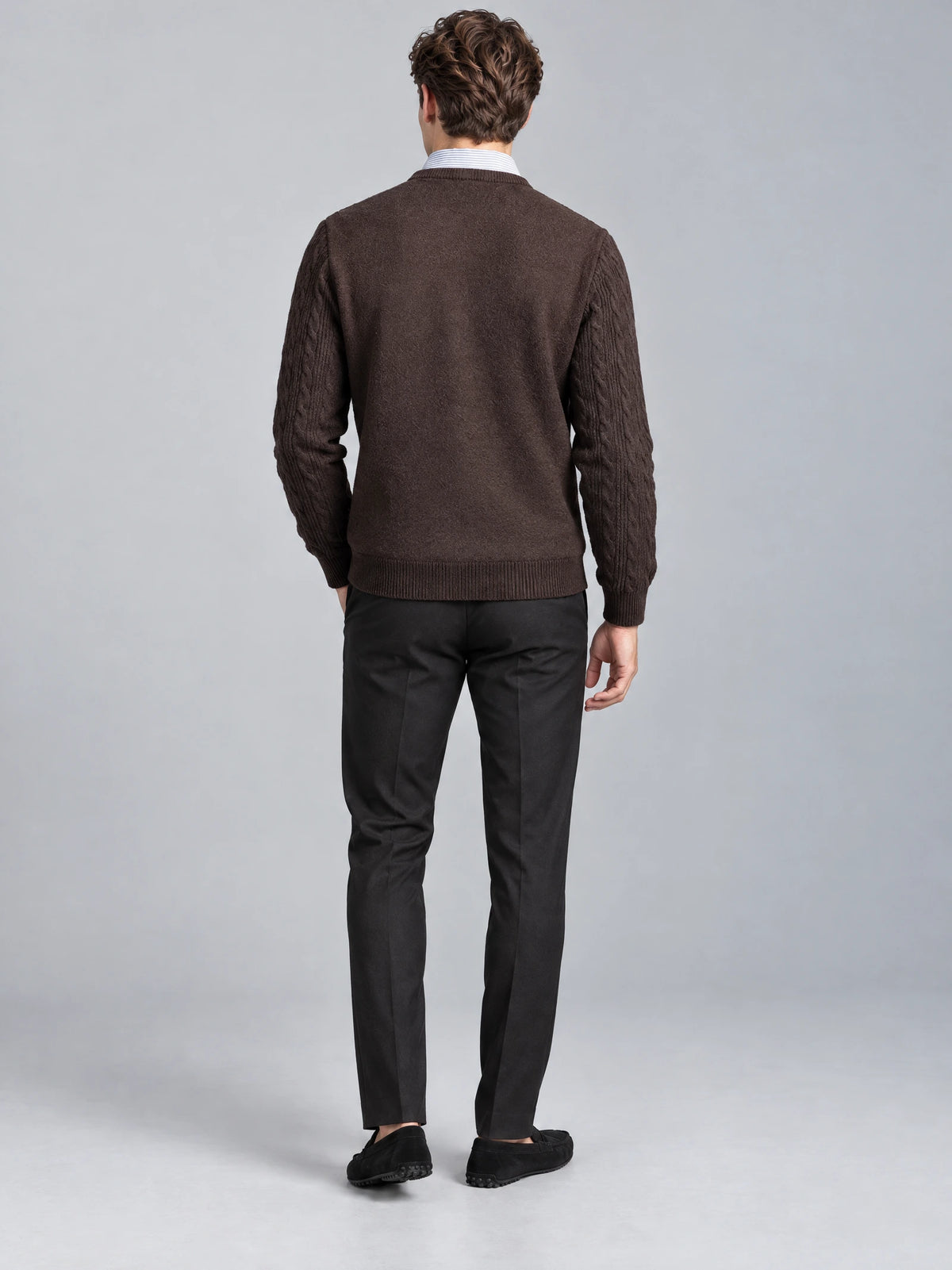 Rear studio view of a model wearing a Brown business casual knitted pullover sweater with textured cable-knit sleeves and ribbed hem.