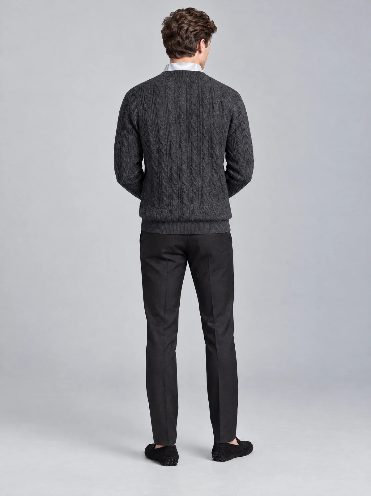 Rear studio view of a model wearing a Charcoal business casual knitted pullover sweater with cable-knit texture and a striped shirt collar.