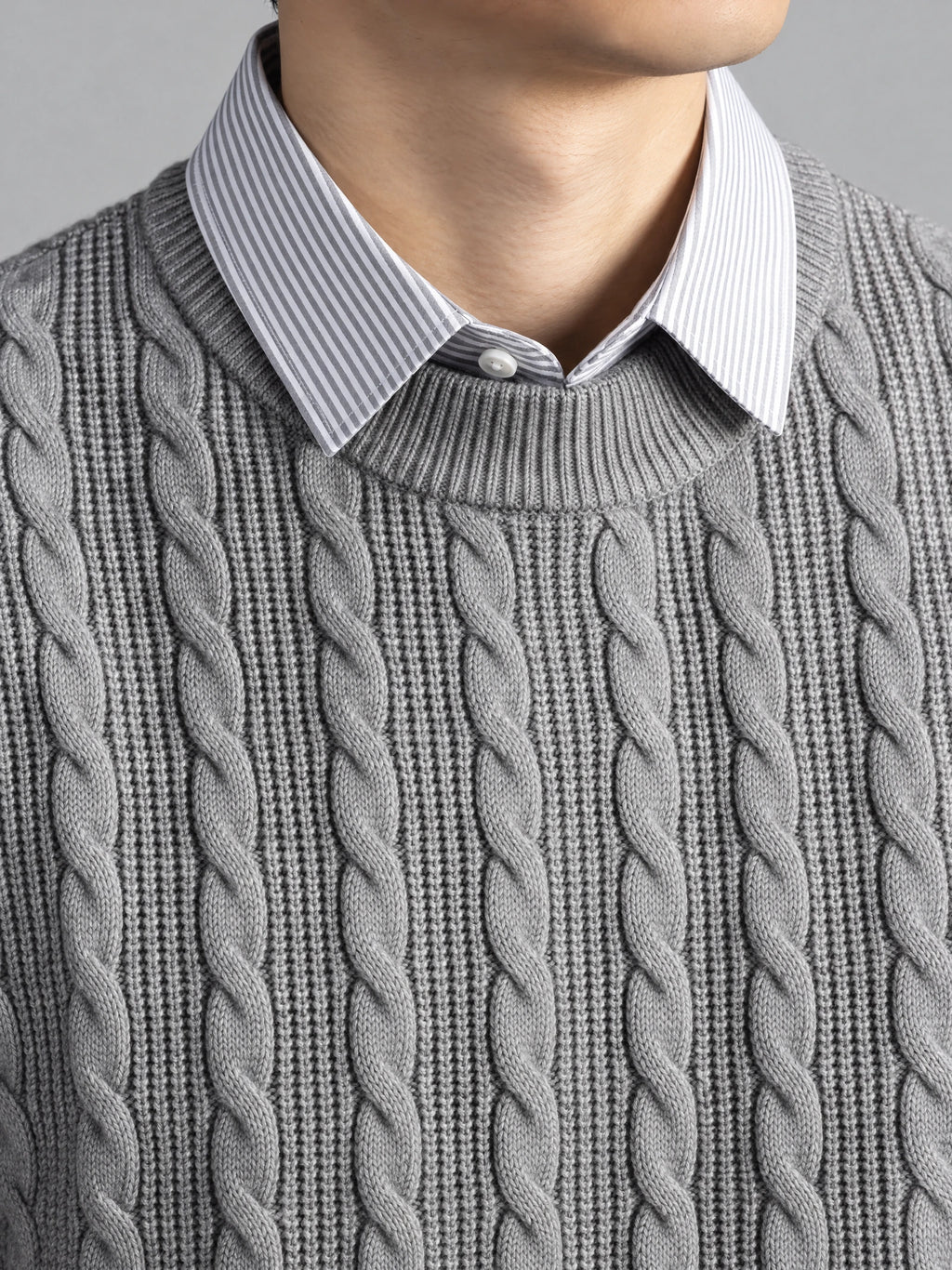 Gray business casual knitted pullover sweater detail showing cable-knit texture, ribbed crew neckline, and faux striped shirt collar.