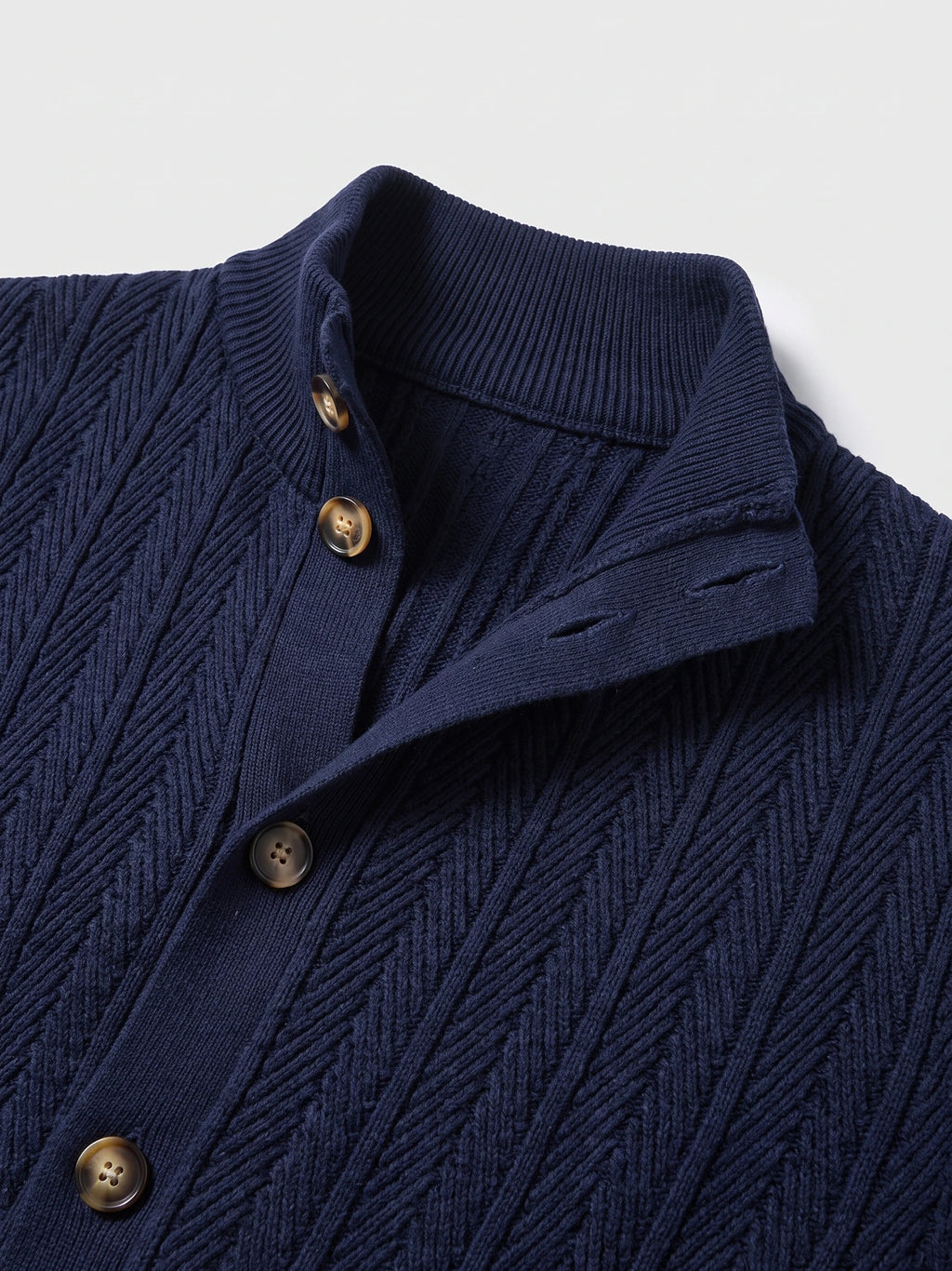 Close-up of a Navy Button Up Cardigan with a ribbed stand collar, four-hole buttons, and textured cable-knit pattern.