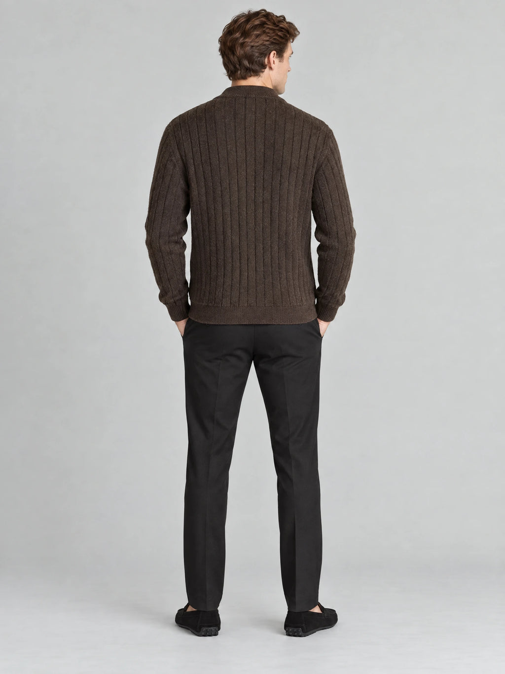 Rear view of a model wearing a Brown cable knit full zip sweater with vertical textured knit panels and ribbed trim.