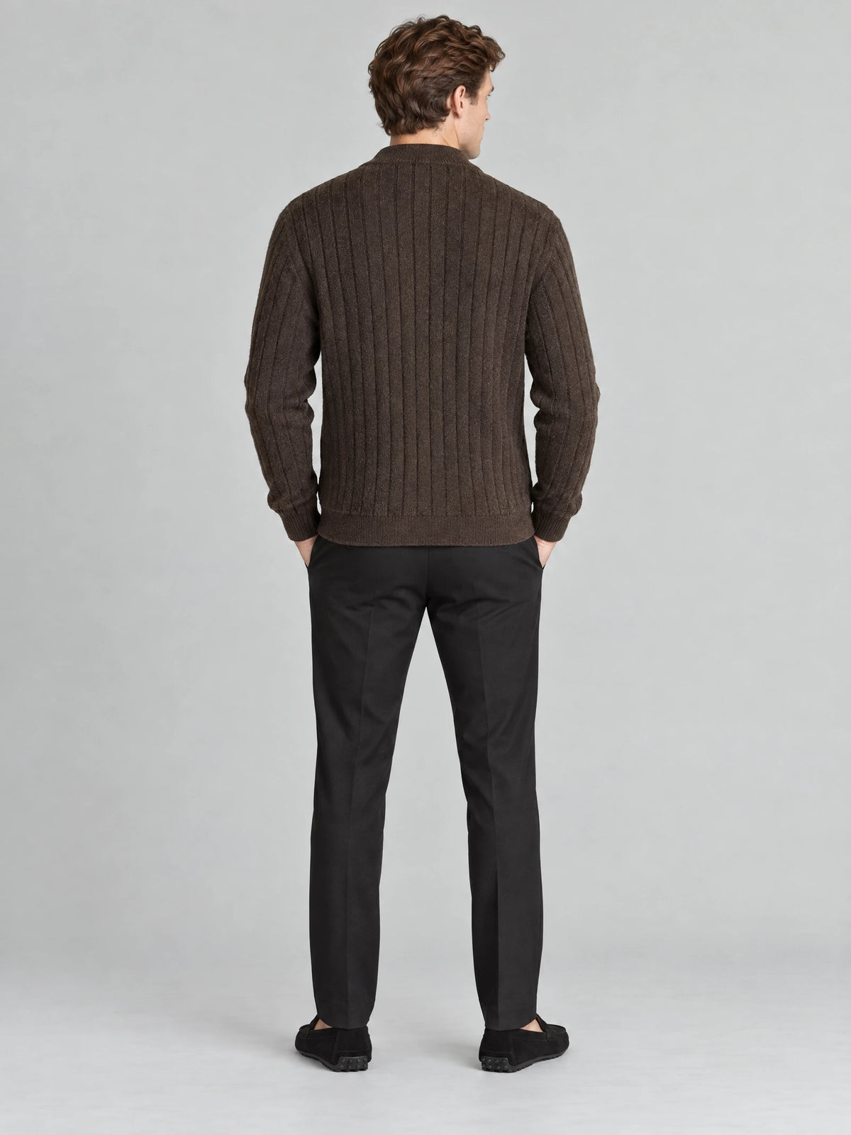 Rear view of a model wearing a Brown cable knit full zip sweater with vertical textured knit panels and ribbed trim.