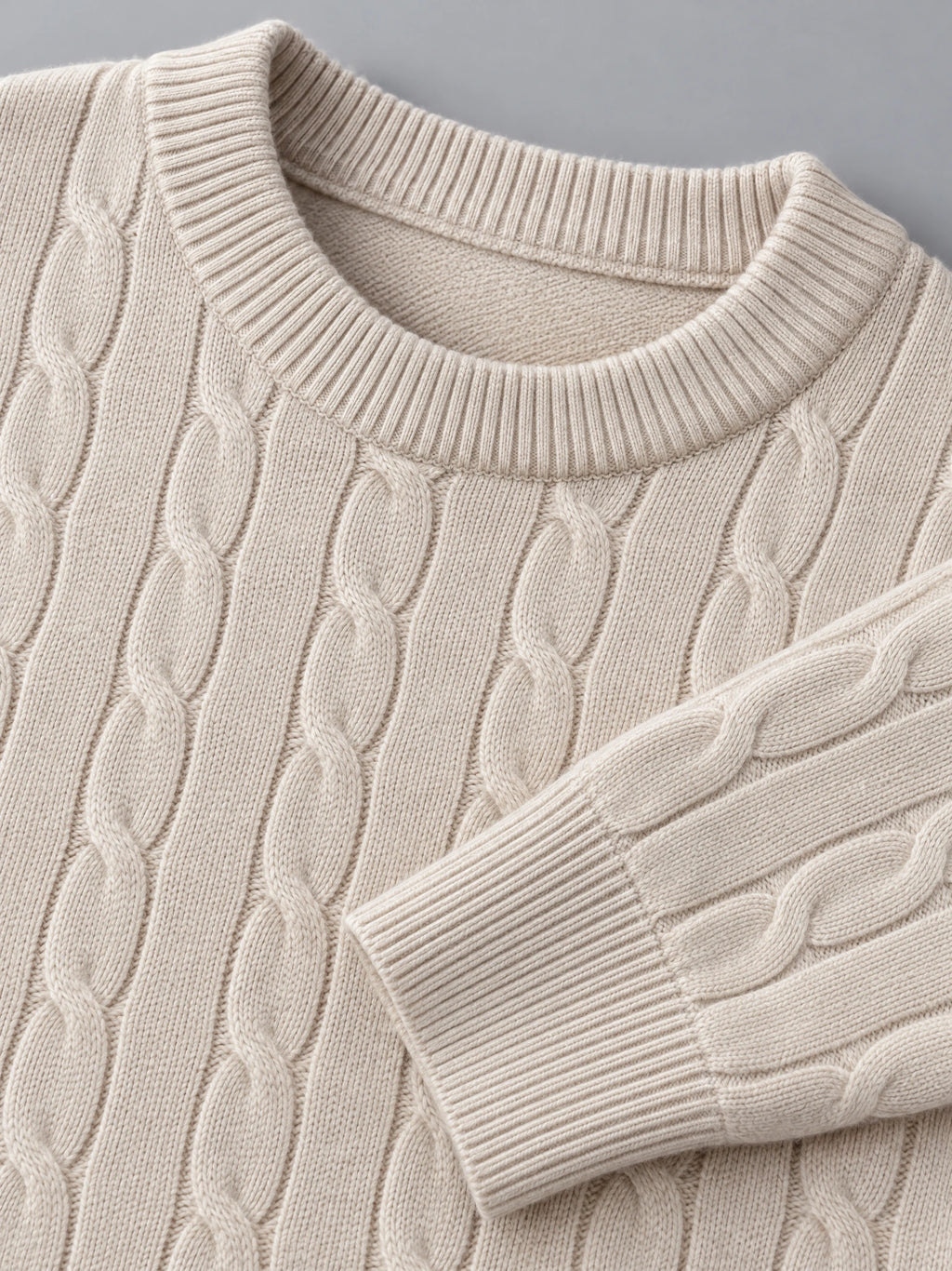 Close-up of the Beige men's cable knit sweater showing its ribbed crewneck, textured cable pattern, and ribbed cuff.