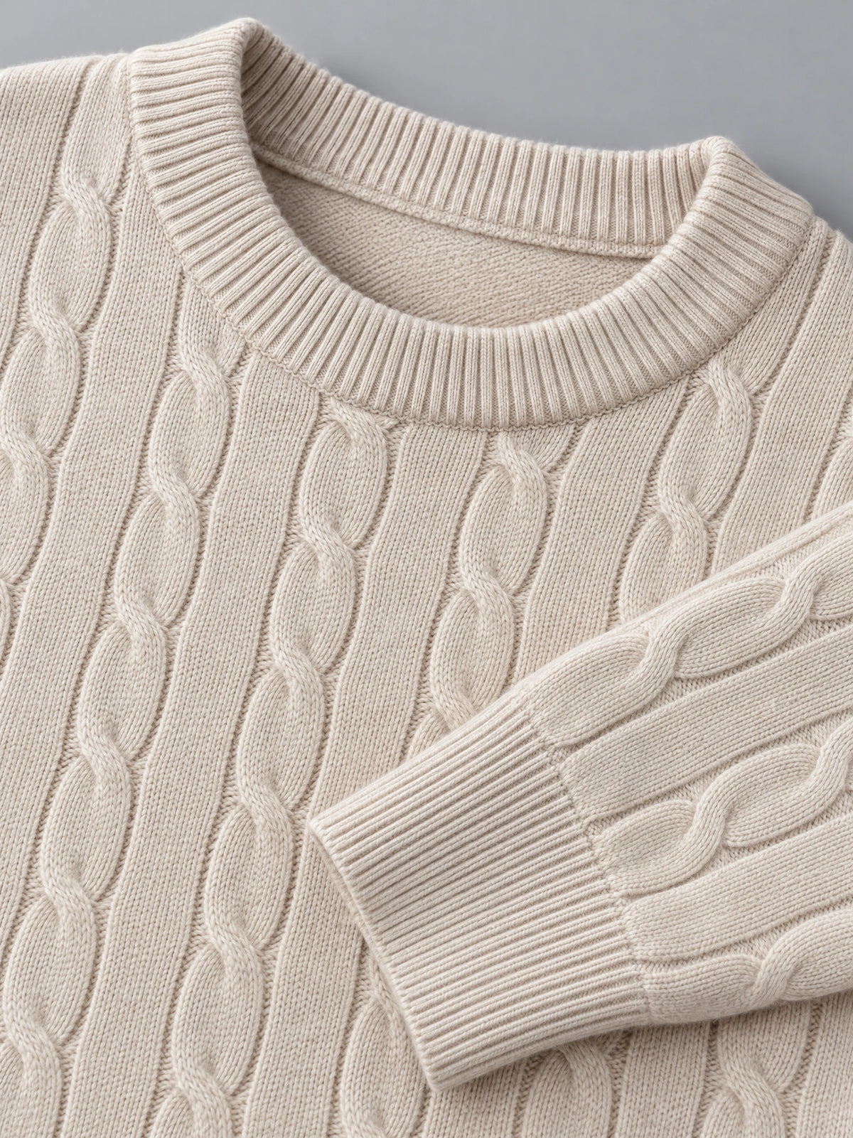 Close-up of the Beige men's cable knit sweater showing its ribbed crewneck, textured cable pattern, and ribbed cuff.