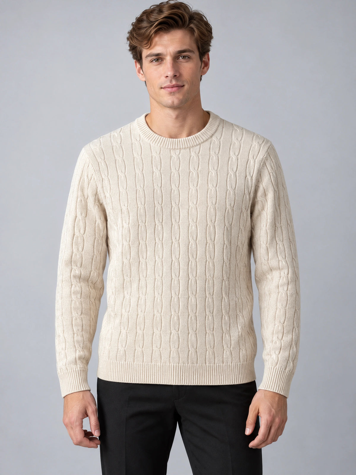 Front studio view of a model wearing a Beige cable knit sweater with a ribbed crewneck, cuffs, and hem.