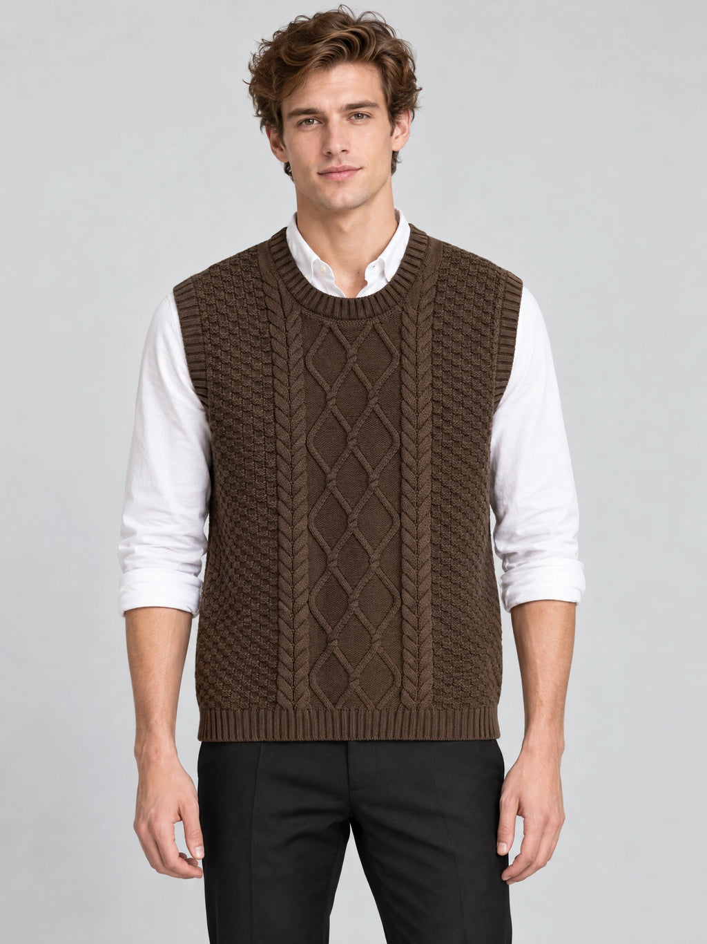 Front studio view of a model wearing a Brown cable knit sweater vest with a ribbed round neck over a collared shirt.