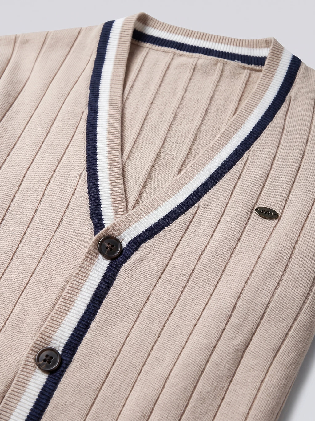 Beige cotton cardigan sweater close-up showing a ribbed V-neck, striped trim, buttons, and vertical knit texture.