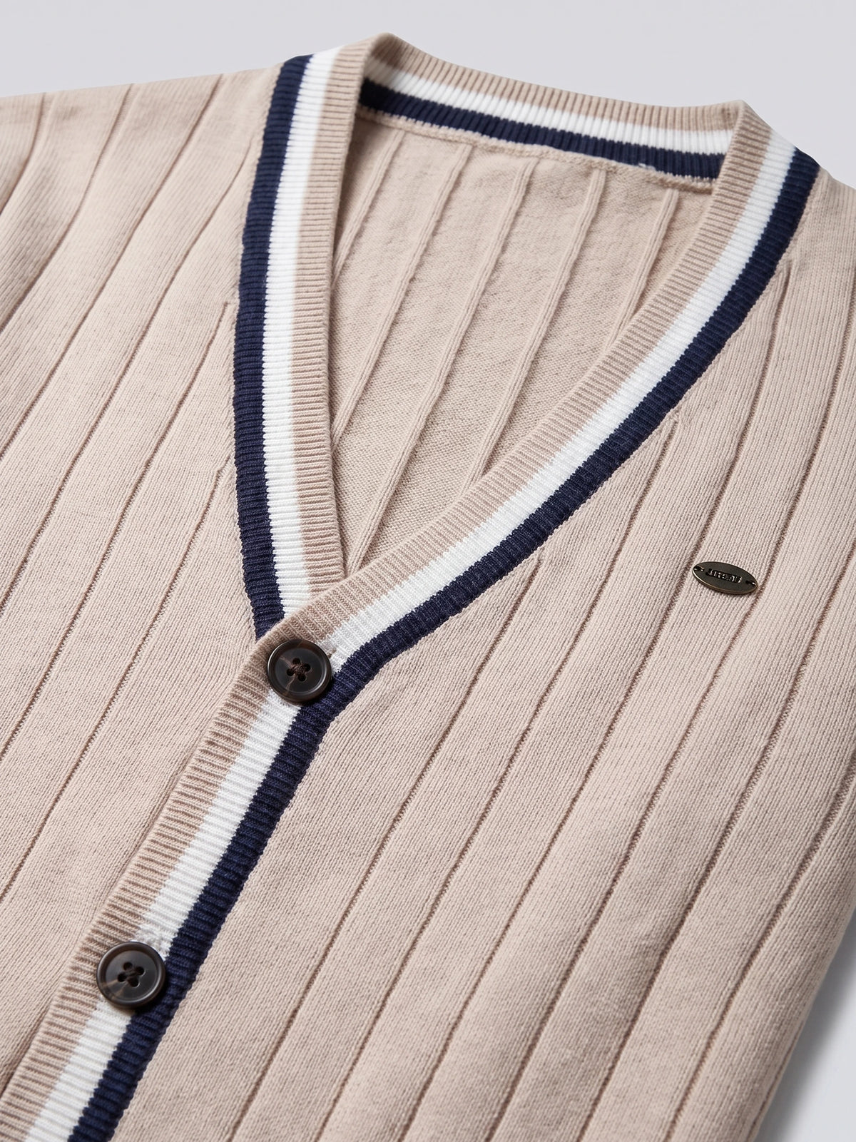 Beige cotton cardigan sweater close-up showing a ribbed V-neck, striped trim, buttons, and vertical knit texture.