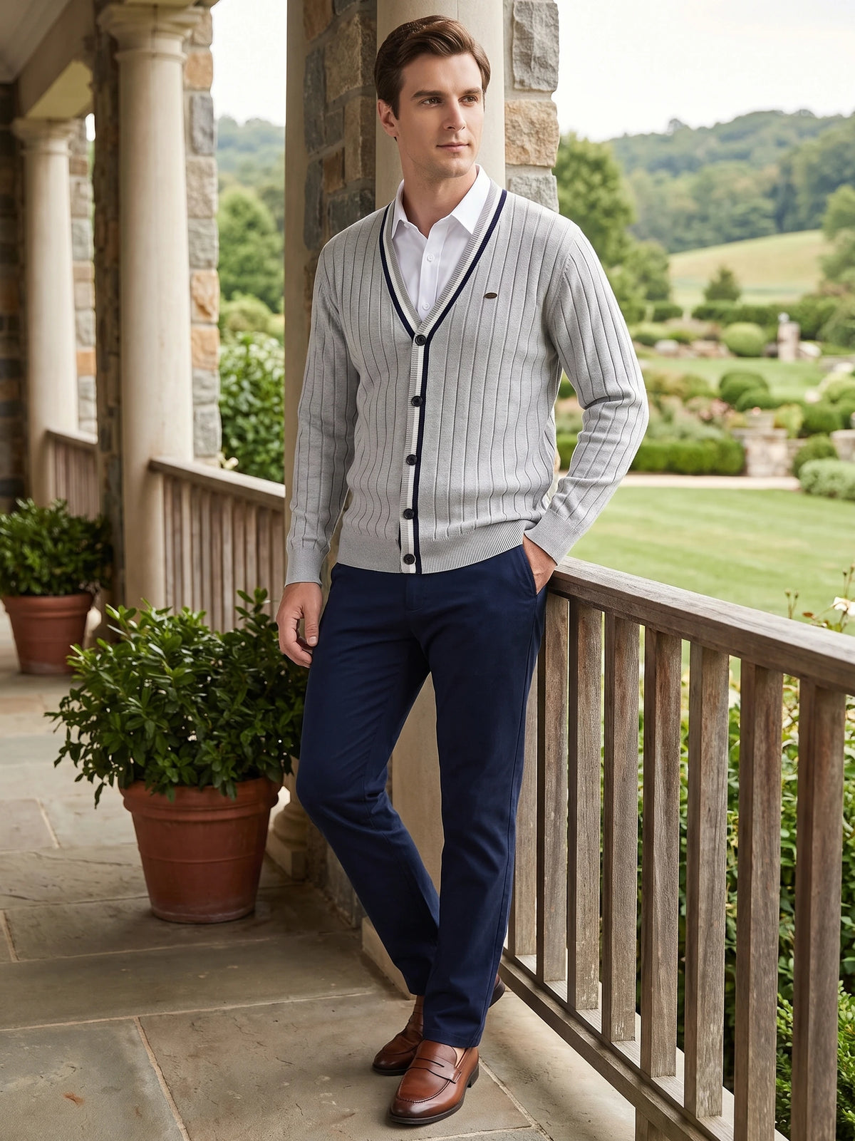 Man wearing a Gray cotton V-neck Cardigan Sweater with vertical knit texture on a stone porch overlooking a landscaped garden.
