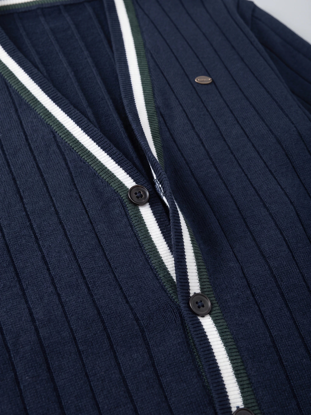 Close-up of a Navy cotton Cardigan Sweater with ribbed knit texture, button front, and striped V-neck trim.