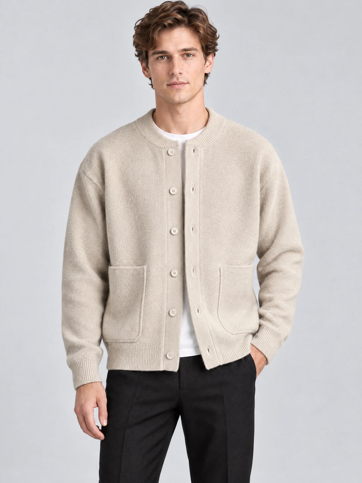 Front studio view of a model wearing a Beige wool Cardigan Sweater with a ribbed round neck, button front, and patch pockets.
