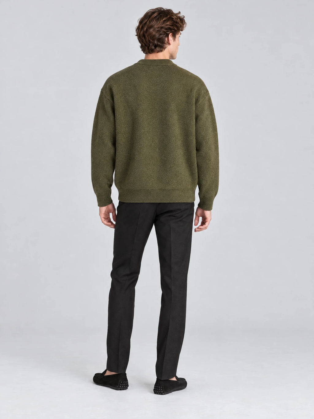 Rear studio view of a model wearing a Green wool Cardigan Sweater with ribbed cuffs and hem.