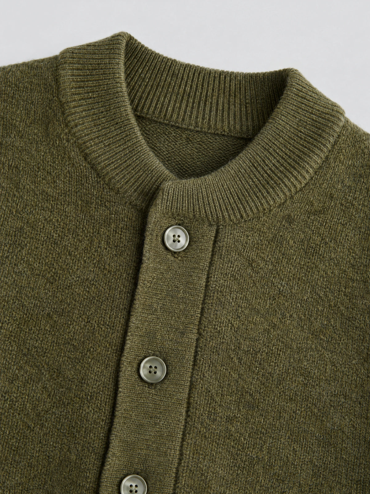 Close-up of the Green wool Cardigan Sweater with a ribbed round neckline and button-front knit detailing.