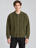 Front studio view of a model wearing a Green wool Cardigan Sweater with a round neck, button front, and patch pockets.