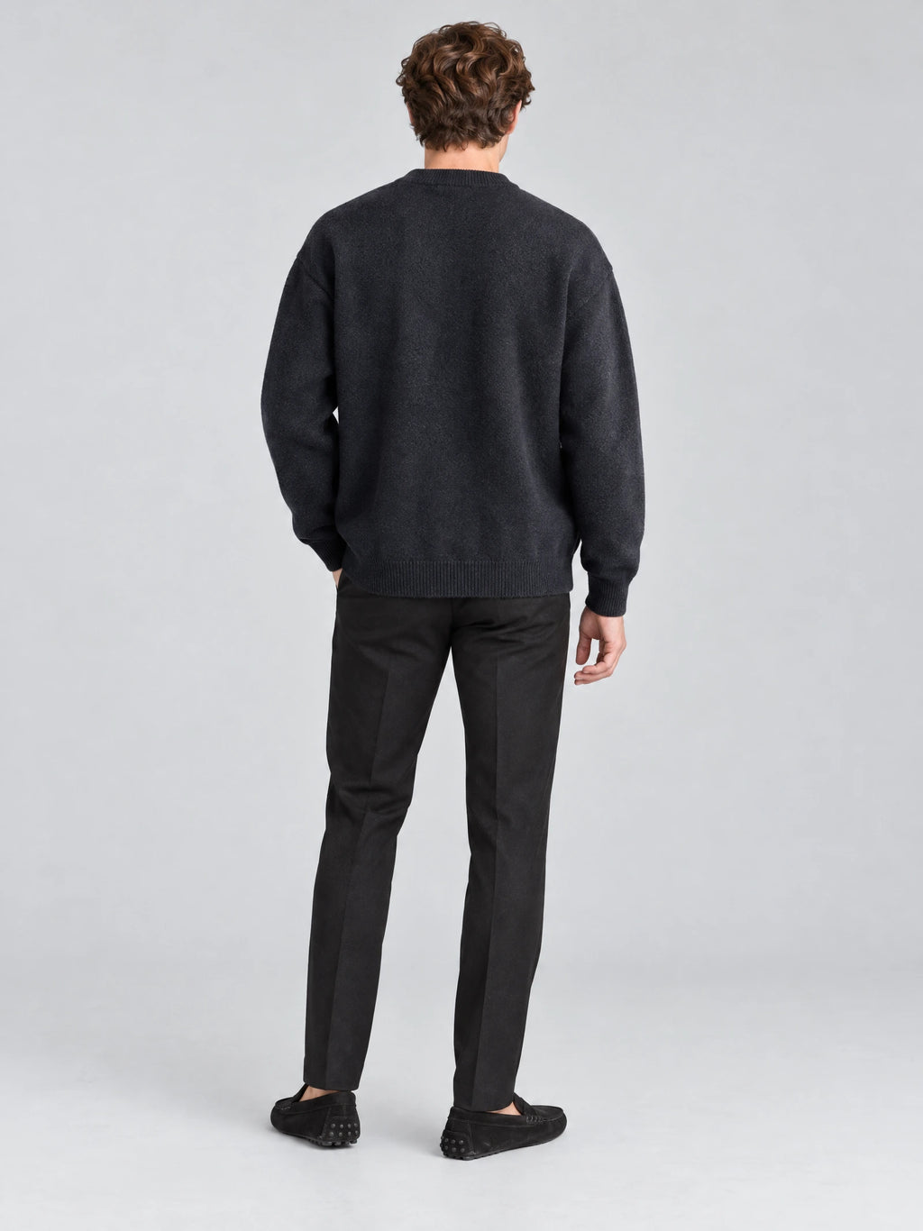Rear studio view of a model wearing a Navy wool Cardigan Sweater with ribbed hem and cuffs.