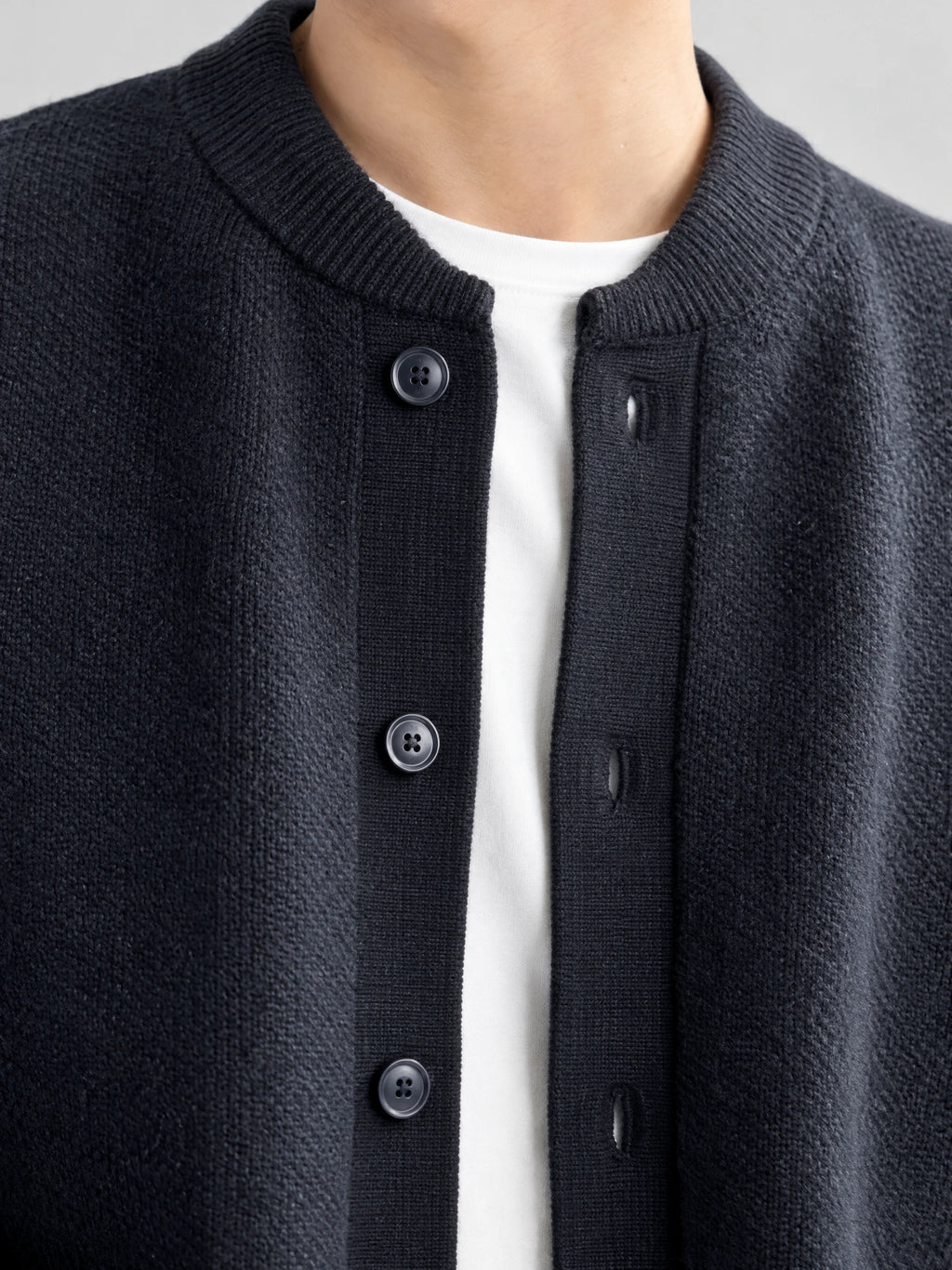 Close-up of a Navy wool Cardigan Sweater showing the ribbed round neckline, knit texture, and button-front placket.