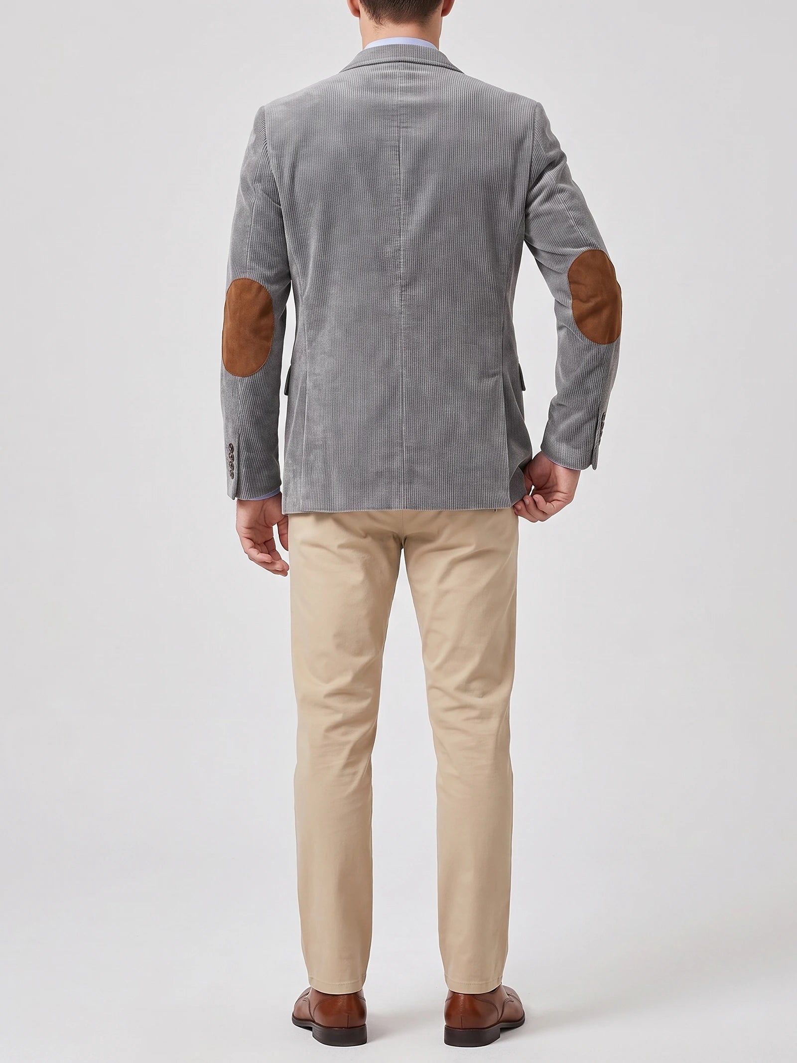Rear studio view of a model wearing a Gray corduroy blazer with a center back seam and elbow patches.