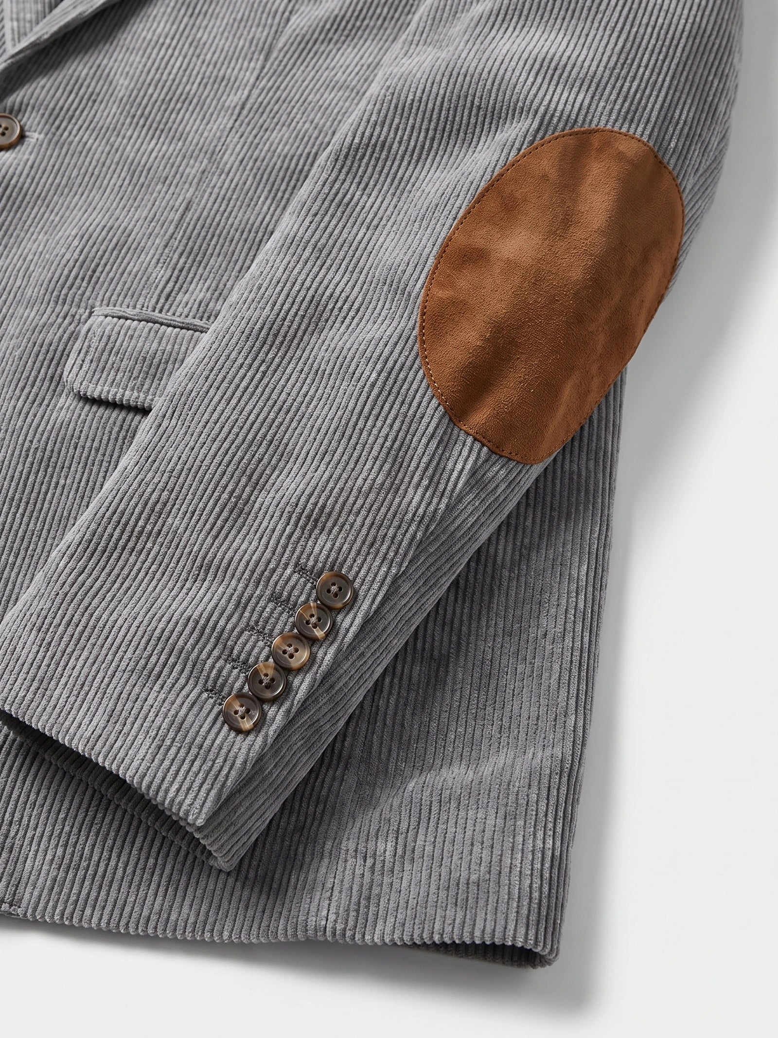 Gray corduroy blazer detail showing ribbed fabric, an elbow patch, flap pocket, and buttoned cuff.