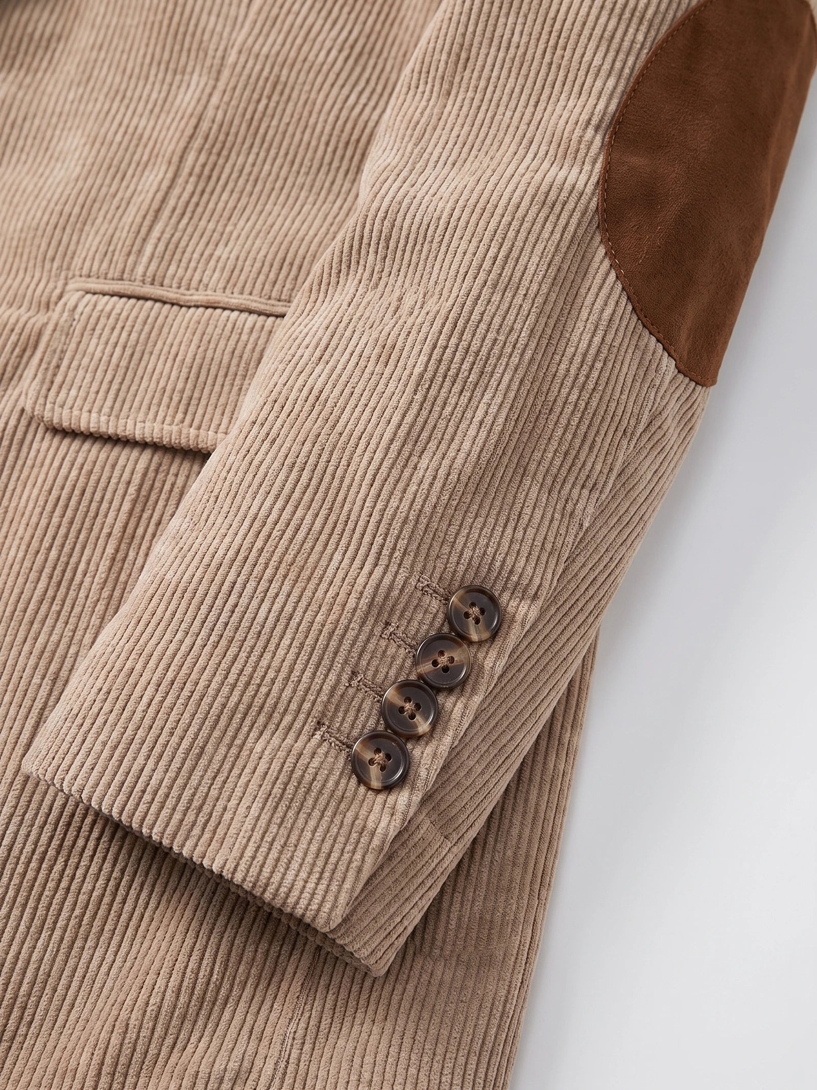 Khaki corduroy blazer detail showing the elbow patch, textured fabric, and four-button cuff.