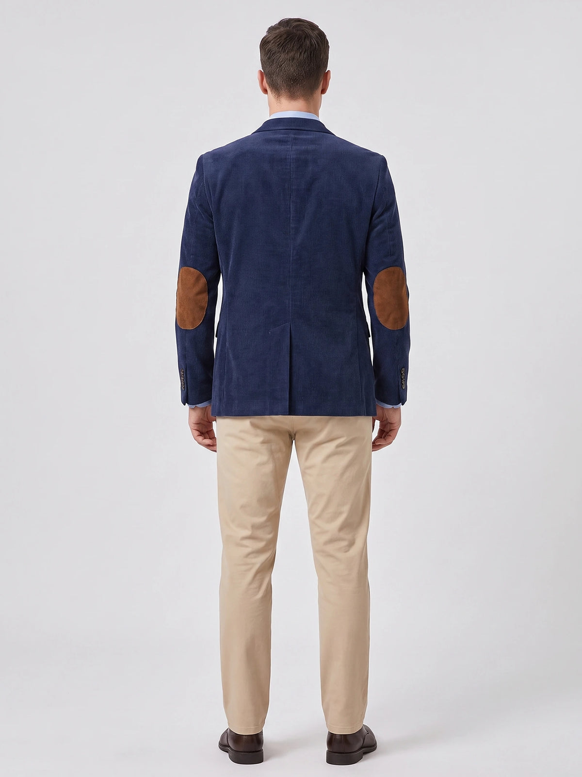 Rear view of a model wearing a Navy corduroy blazer with elbow patches and a center back vent.