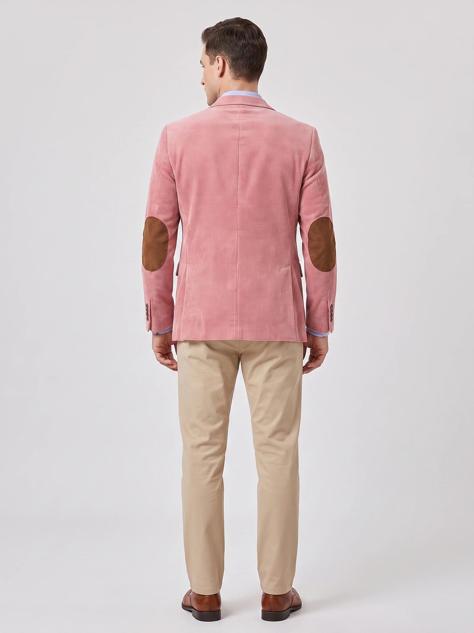 Rear studio view of a model wearing a Pink corduroy blazer with elbow patches and a center back seam.