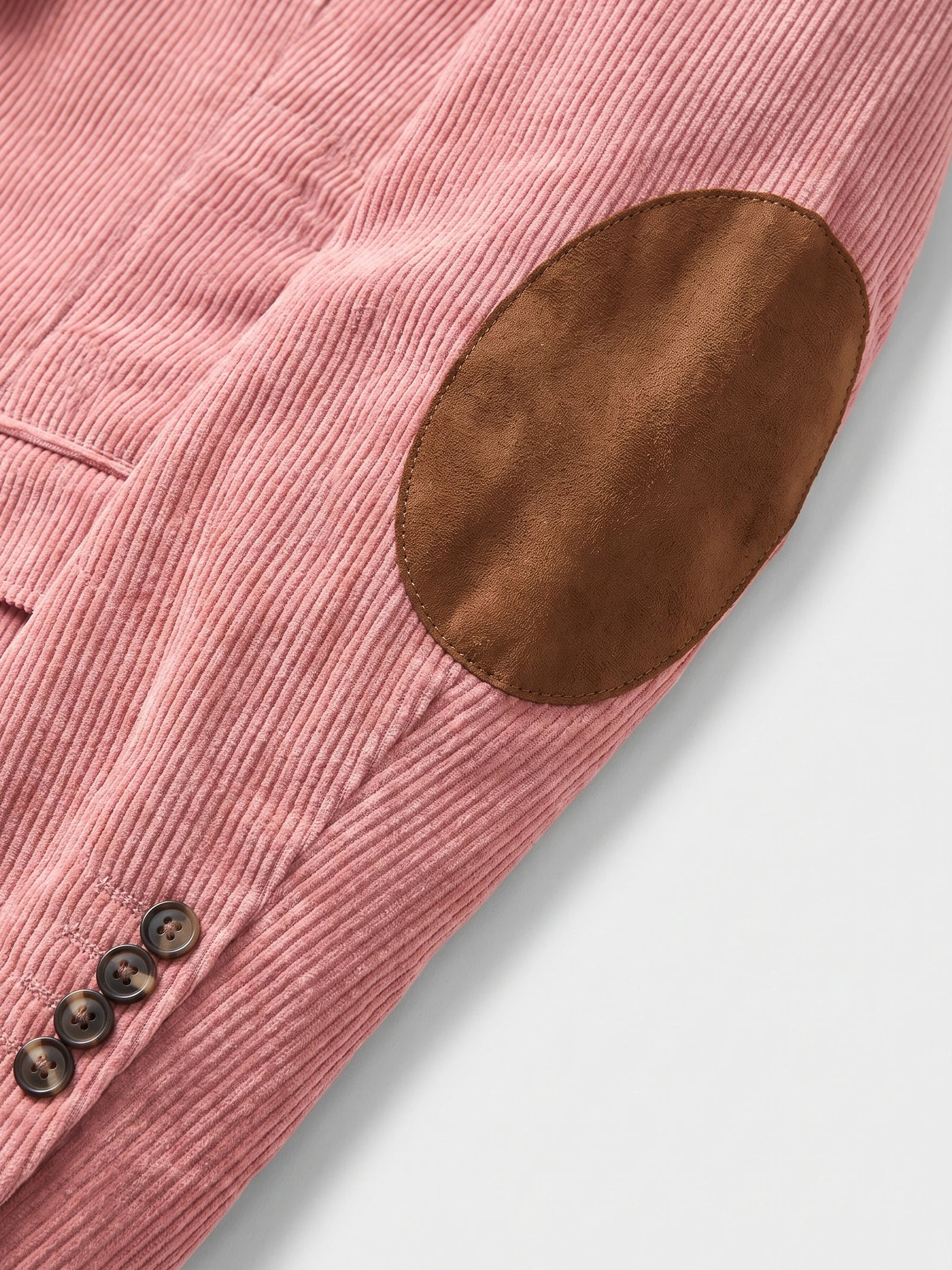 Close-up of a Pink corduroy blazer sleeve with a stitched elbow patch and cuff buttons.