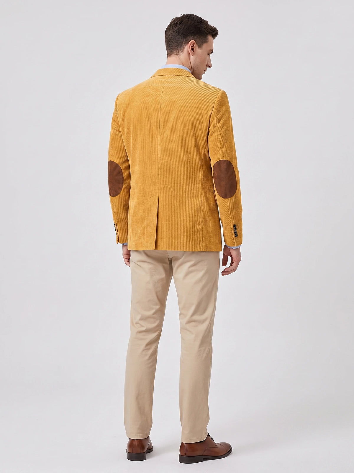 Rear studio view of a model wearing a Yellow corduroy blazer with elbow patches and a center back vent.