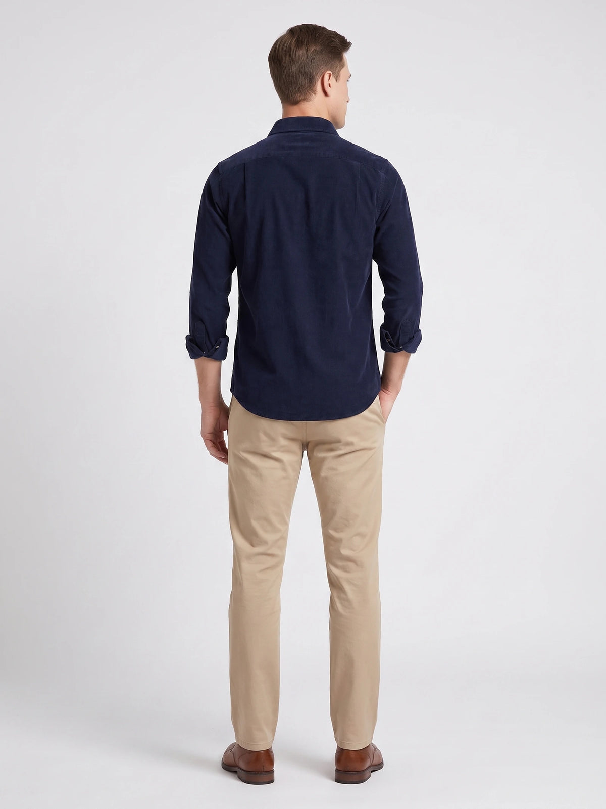 Rear studio view of a model wearing a Navy cotton corduroy shirt with rolled cuffs.