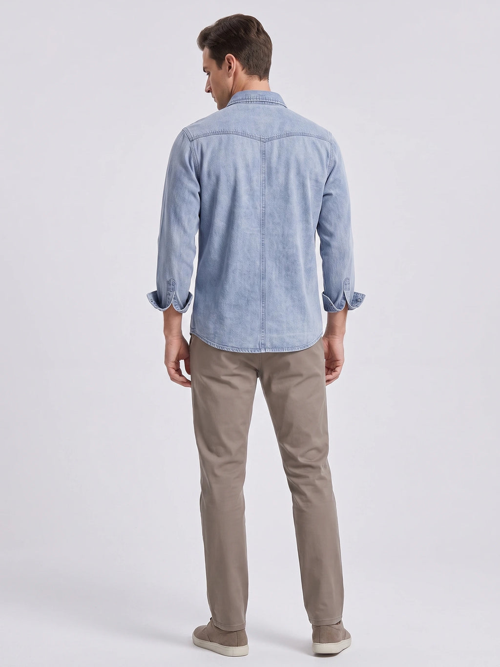 Rear view of a model wearing a Blue cotton denim Cowboy Shirt with long sleeves, back yoke stitching, and a curved hem.