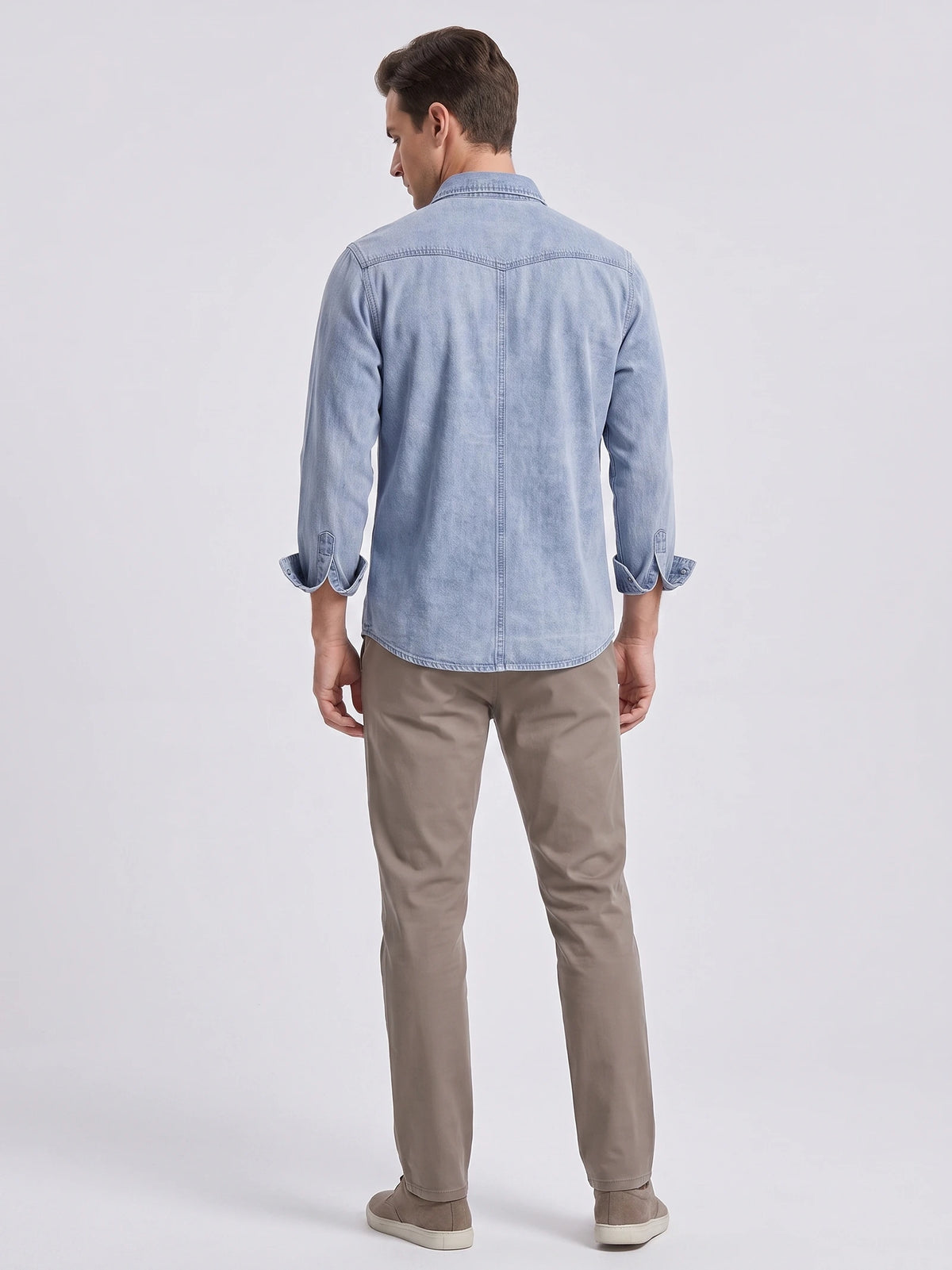 Rear view of a model wearing a Blue cotton denim Cowboy Shirt with long sleeves, back yoke stitching, and a curved hem.
