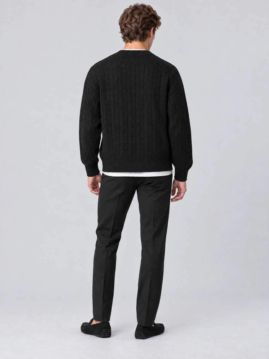 Rear studio view of a model wearing a Black crewneck cardigan with a textured cable-knit back and ribbed trim.