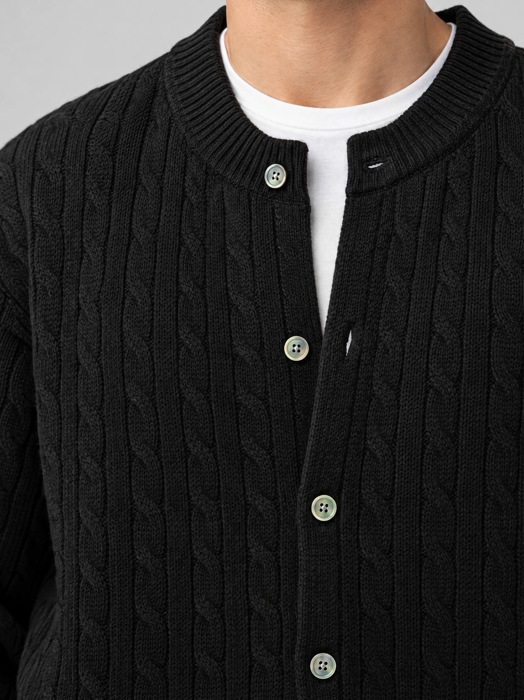 Close-up of a Black men’s crewneck cardigan with cable-knit texture, ribbed collar, and button-front closure.