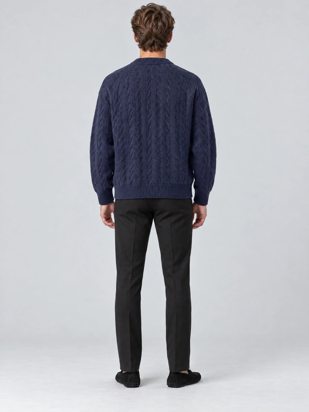 Rear studio view of a model wearing a Navy crewneck cardigan with cable-knit texture and ribbed cuffs and hem.
